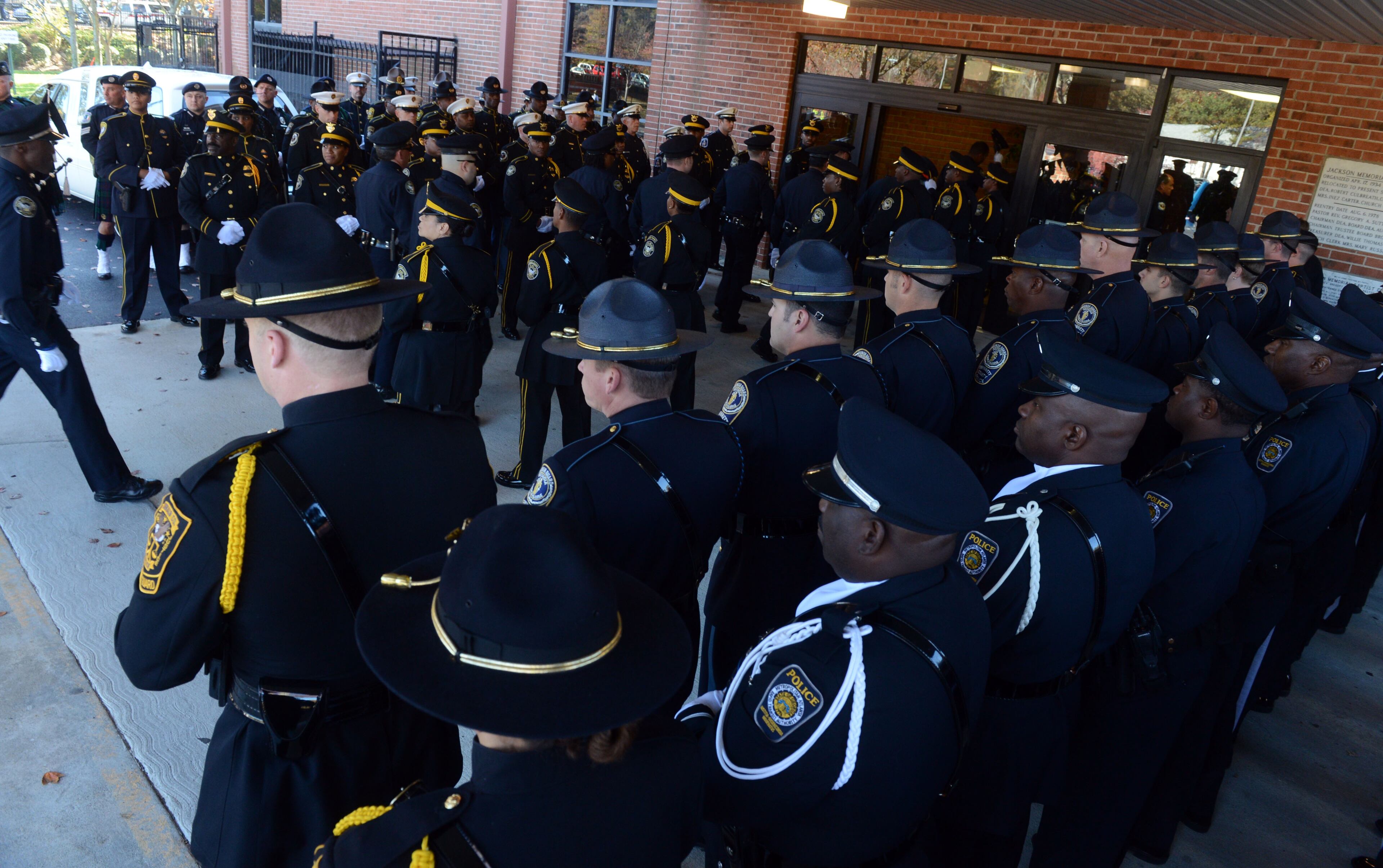 Honor Guards from several law enforcement agencies including Atlanta Police, Dekalb Police, MARTA police and others stand at attention as APD officers enter the church.