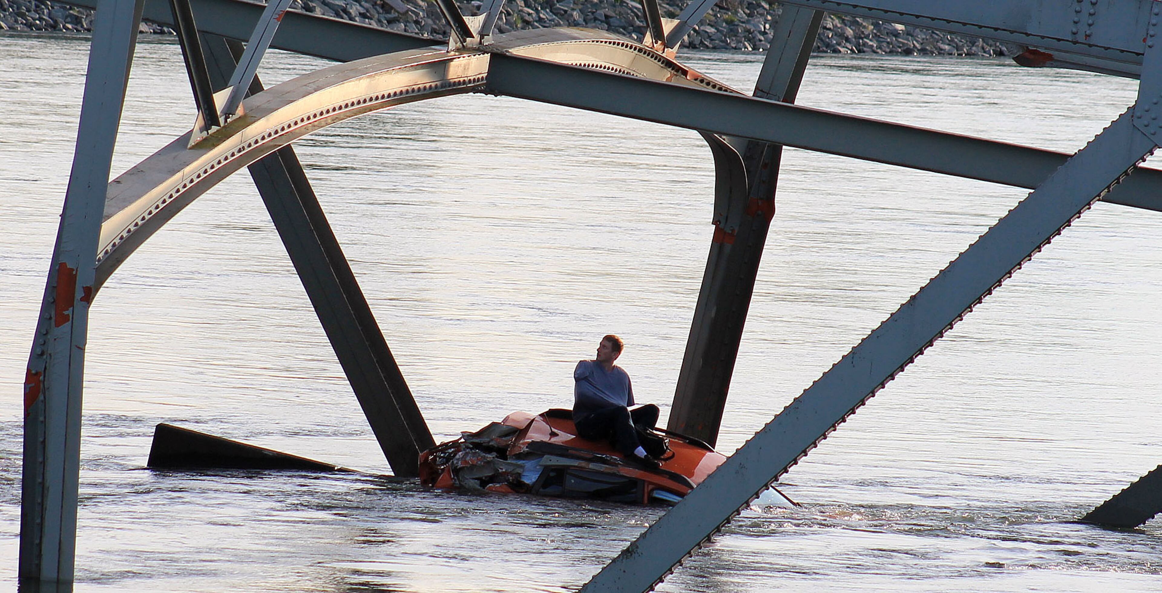 In this photo provided by Francisco Rodriguez, a man is seen sitting atop a car that fell into the Skagit River after the collapse of the Interstate 5 bridge there minutes earlier Thursday, May 23, 2013, in Mount Vernon, Wash. (AP Photo/Francisco Rodriguez)