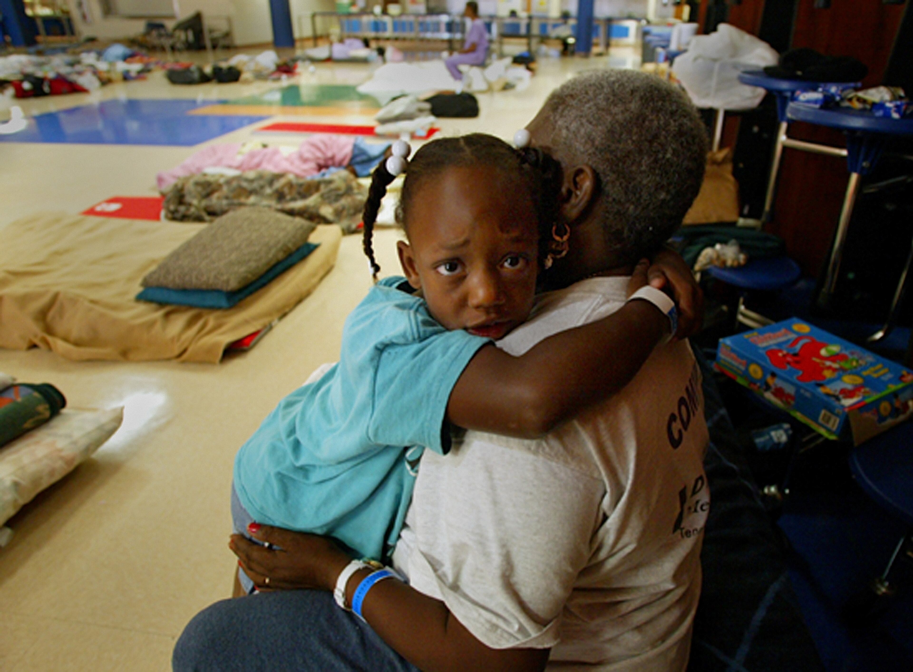 10/26/05 hur wil 1 Staff photo by Bob Shanley / The Palm Beach POST 0014146A With story by Lona O'Connor---BOCA RATON--- 5-Year-ol Elenora Williams hugs her great-grandmother Rosa Angeletta (cq) as the pair start their day, Wednesday in the Red Cross shelter in the cafeteria at Park Vista High School. They are evacuees from the Bywater area of New Orleans who had been staying at Palm Meadows until Sunday when the Red Cross moved them to the Park Vista shelter becaues of Hurricane Wilma. 10/26/2005 NOT FOR DISTRIBUTION OUTSIDE COX PAPERS. OUT PALM BEACH, BROWARD, MARTIN , ST. LUCIE, INDIAN RIVER AND OKEECHOBEE COUNTIES IN FLORIDA. OUT ORLANDO. OUT TV, OUT MAGAZINES, OUT TABLOIDS, OUT WIDE WORLD, OUT INTERNET USE. NO SALES. Images of the victims of Hurricane Katina inspired many to come to the aid of New Orleans, including young teachers. (AJC File)