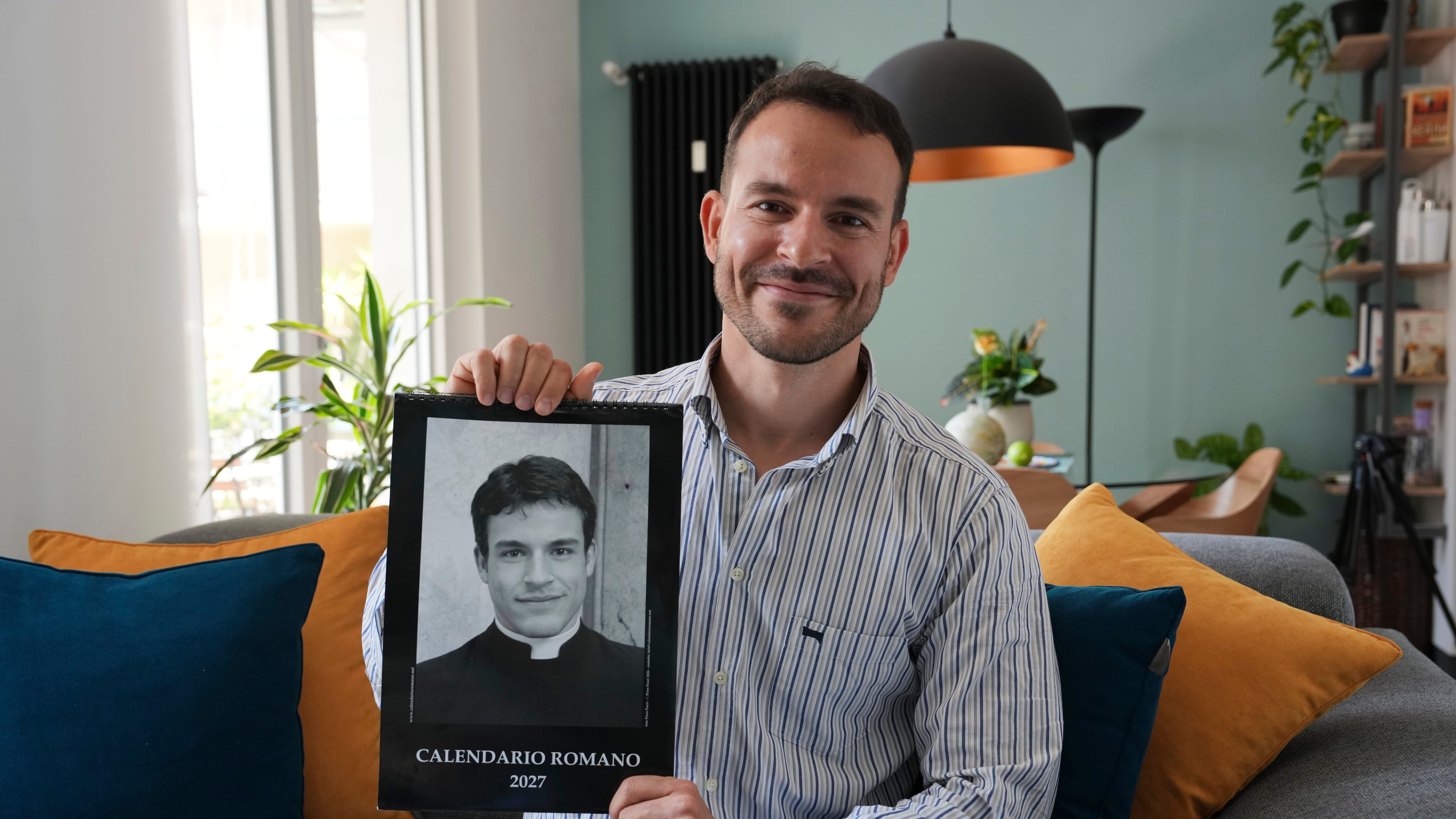 Giovanni Galizia poses with the 'Calendario Romano' calendar that has for two decades been a bestseller in Rome’s souvenir shops, at his home in Verona, Italy, Wednesday, May 20, 2026. (AP Photo/Luca Bruno)