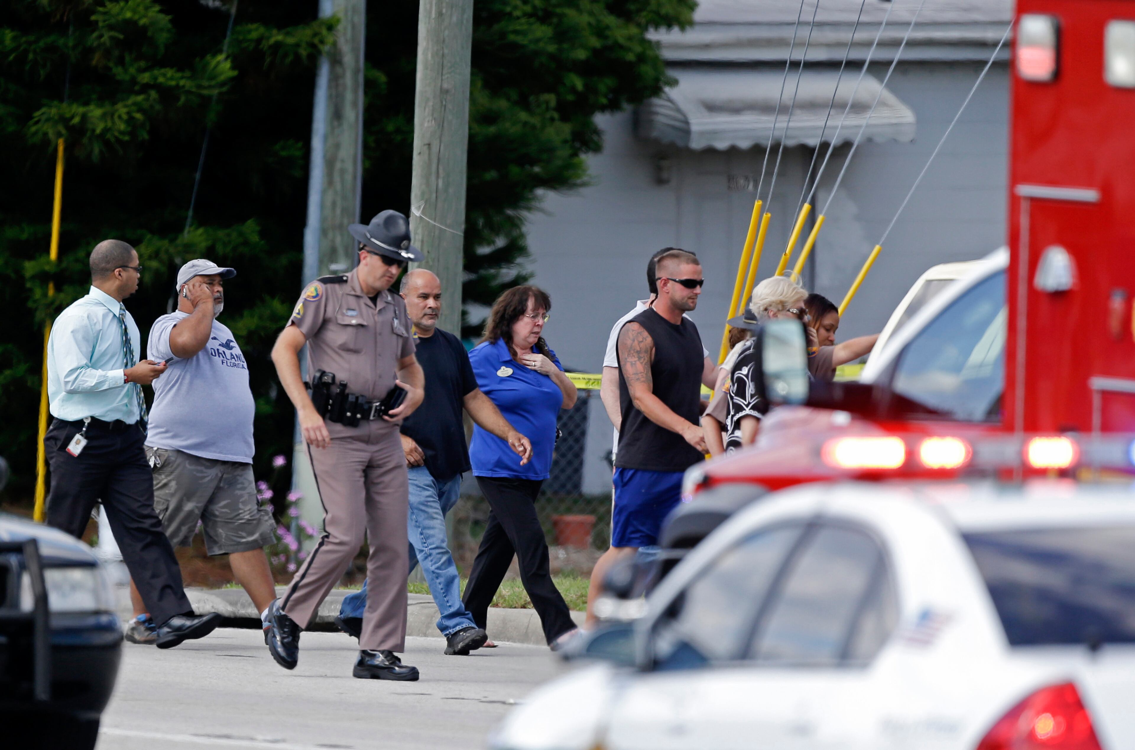 A Florida state trooper, center, escorts a group of parents to a day care center to pick up their children after a vehicle crashed into the center, Wednesday, April 9, 2014, in Winter Park, Fla. (AP Photo/John Raoux)