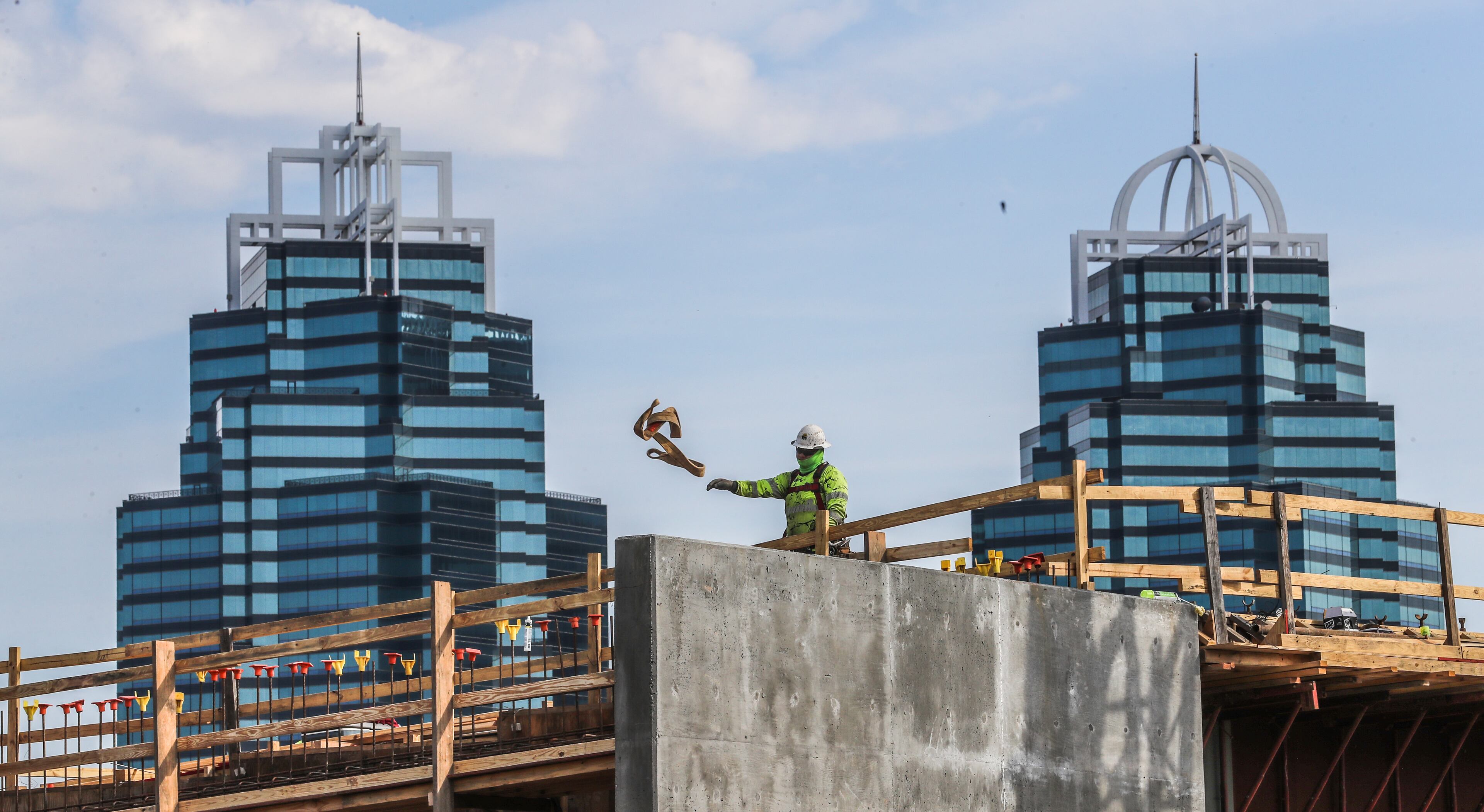 April 7, 2021 Sandy Springs: Getting in a day’s work before the rain comes, a lone construction worker throws aside a strap above Ga. 400 at the rising $800 million dollar, I-285 interchange at Ga. 400 against the backdrop of the King and Queen buildings of Concourse at Landmark Center. (John Spink / John.Spink@ajc.com)