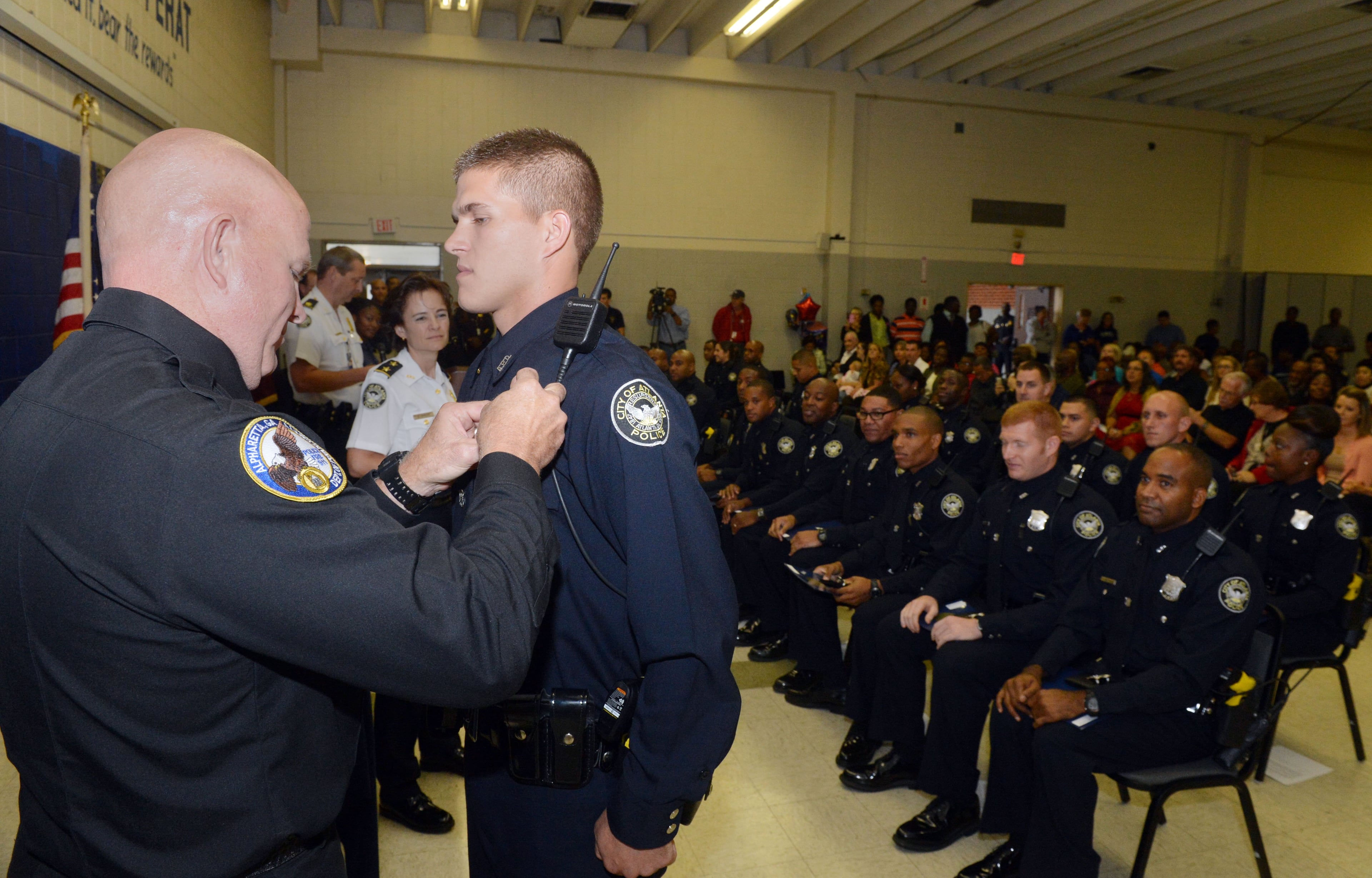 Alpharetta Deputy Director of Public Safety Keith Sanders, pins his son Joshua Sanders during the ceremony.The Atlanta Police Department swore in officers with Class #232 at the Atlanta Police Training Academy on Thursday, October 17, 2013. Twenty-six officers participated in the ceremony that concludes 22 weeks of rigorous training at the Atlanta Police Academy. Training consisted of classroom courses in constitutional law, local and state laws, Atlanta Police Department policy and procedure, hands-on defensive tactics, arrest techniques and daily physical fitness. Next, these officers will experience 12 weeks of field training with veteran officers. KENT D. JOHNSON / KDJOHNSON@AJC.COM