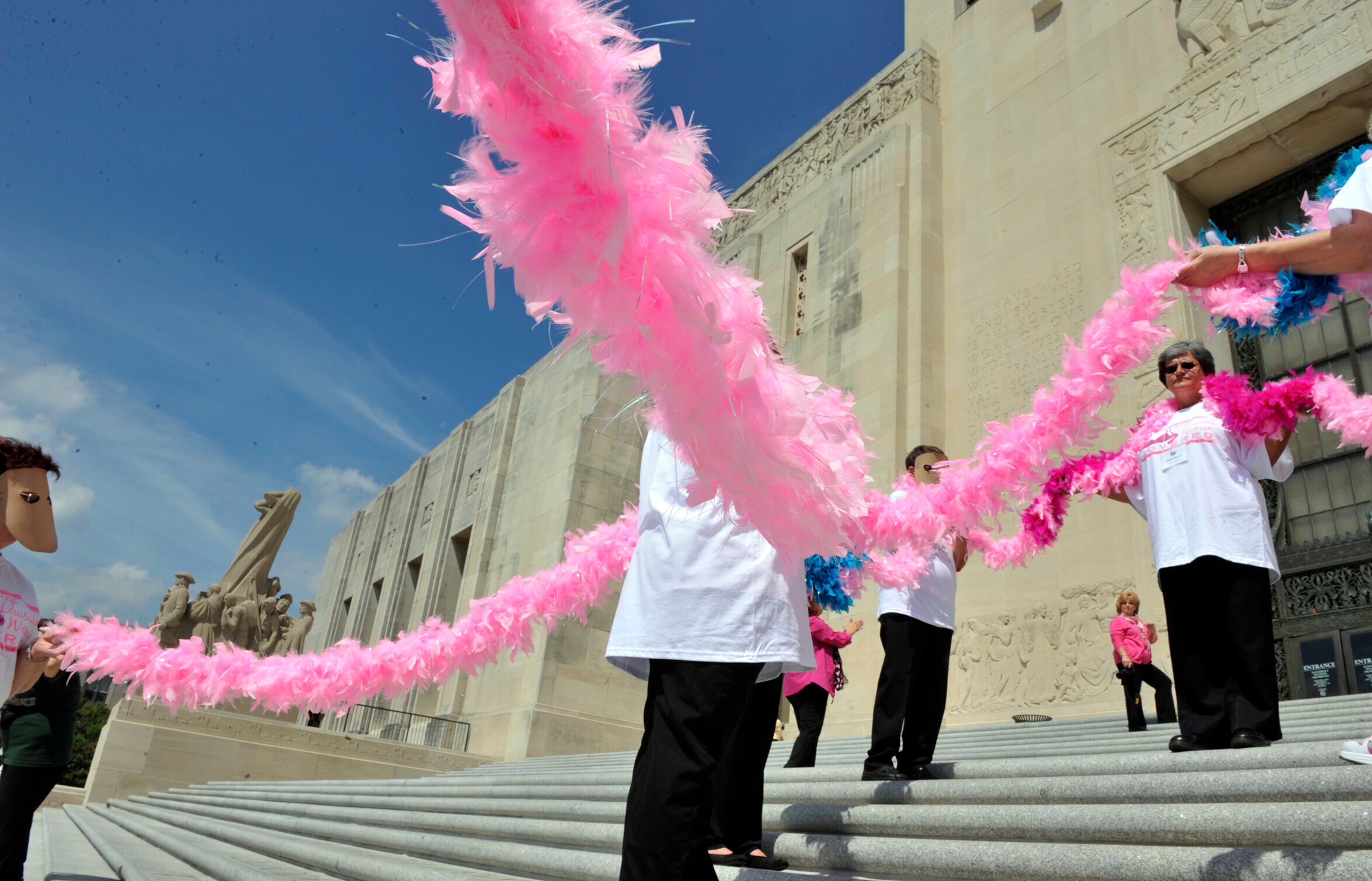 People hold a large pink feather ribbon for emphasis while gathering for a rally on the State Capitol Building steps to bring awareness to breast and cervical cancer screening budget cuts in Baton Rouge, La. (Bill Feig/The Advocate via AP 2012)