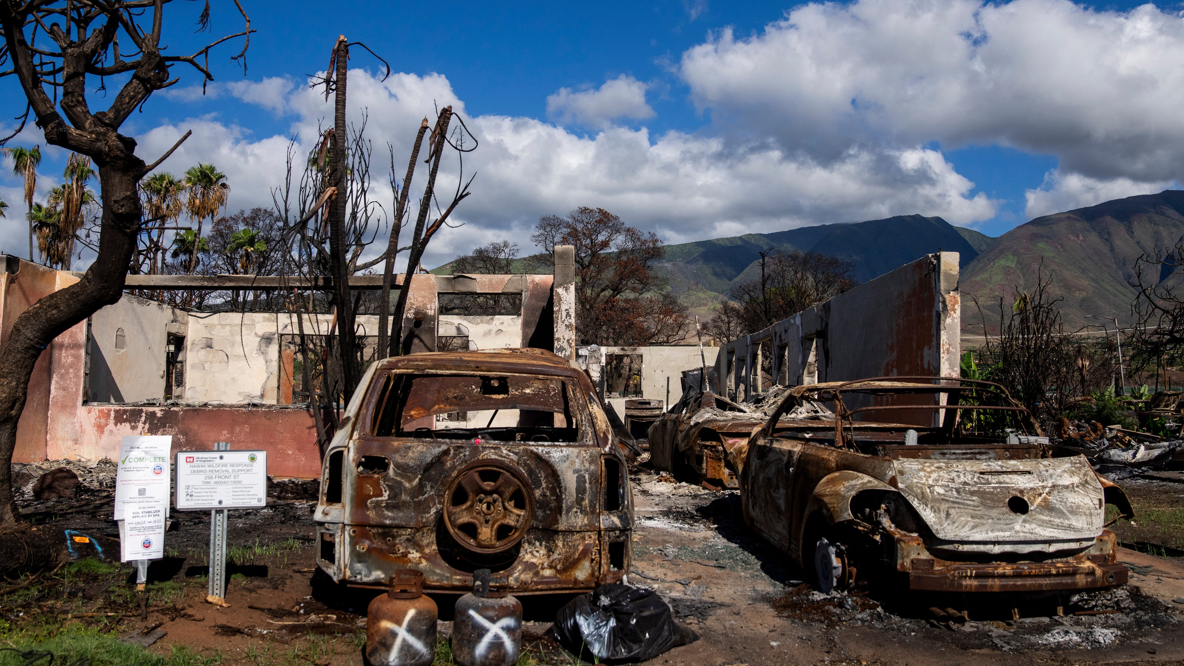 FILE - Burned cars and propane tanks with markings on them sit outside a house destroyed by wildfire, Friday, Dec. 8, 2023, in Lahaina, Hawaii. (AP Photo/Lindsey Wasson, File)