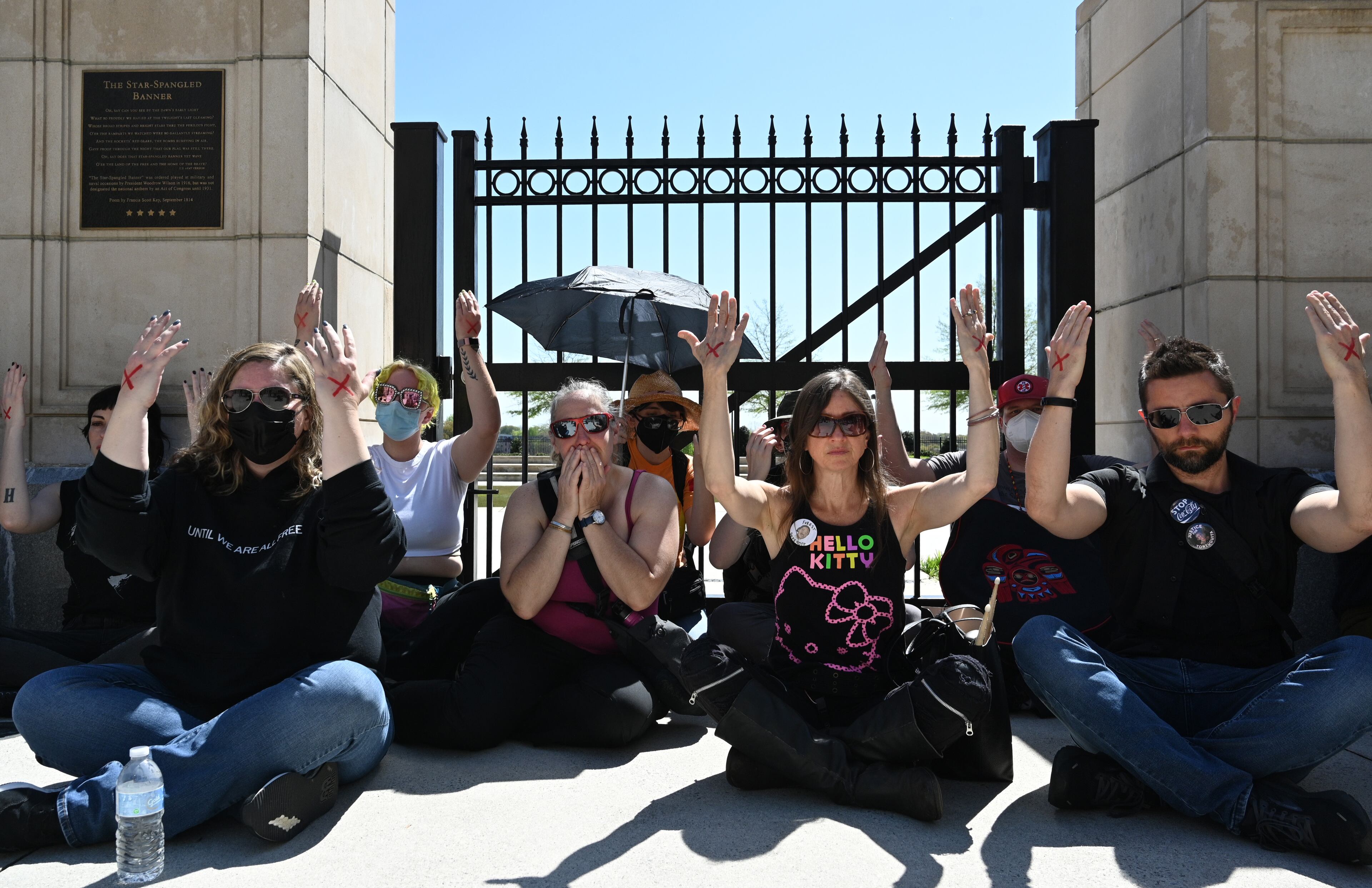 Participants hold up their hands as they participate in a sit-in demonstration during the Justice for Tortuguita Rally at Liberty Plaza across from the Georgia Capitol, Saturday, March 25, 2023, in Atlanta. They were showing how activist Manuel Tortuguita Terán was sitting when killed by law enforcement authorities in January near the planned site of Atlanta's public safety training center. (Hyosub Shin / Hyosub.Shin@ajc.com)
