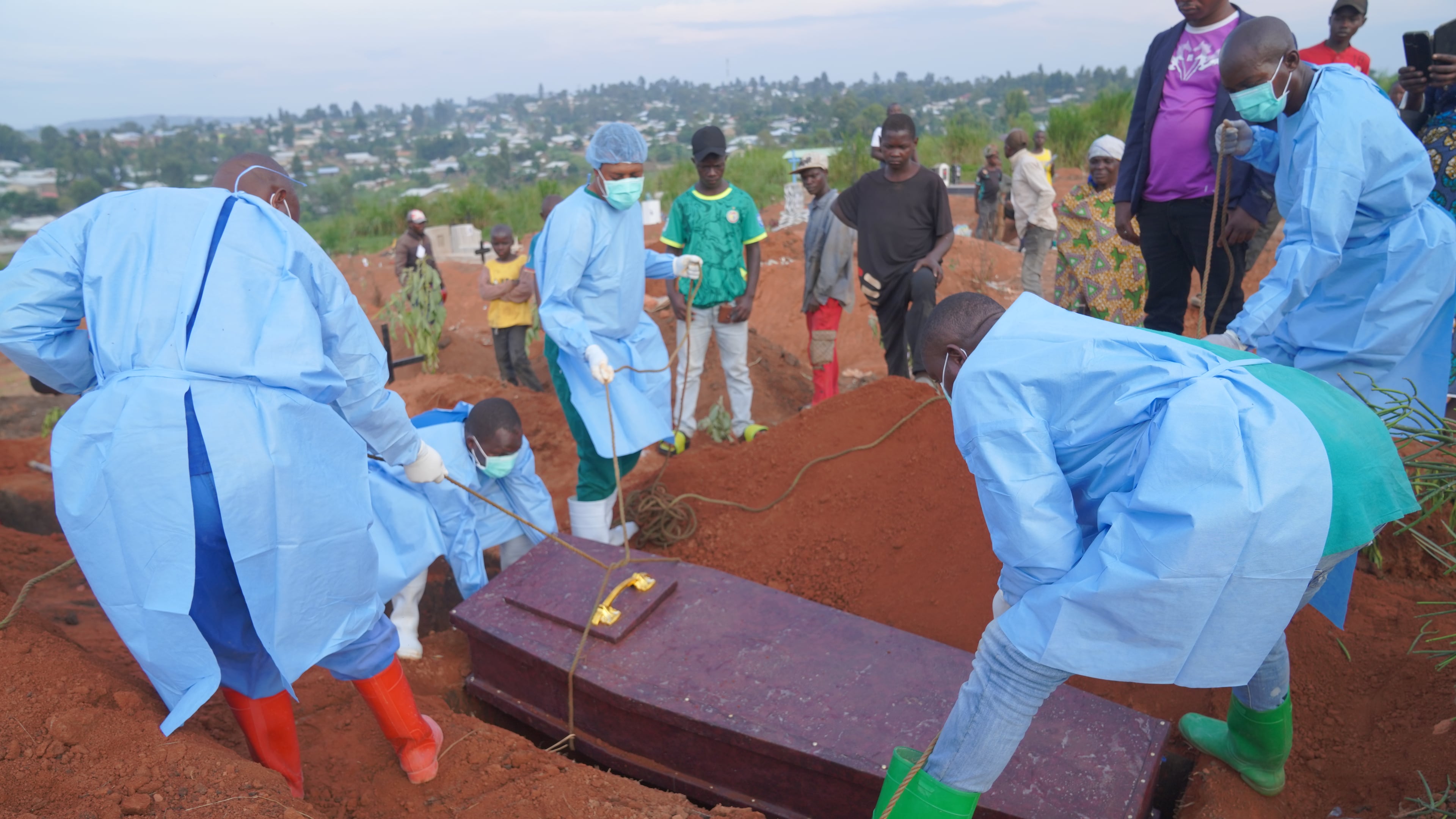 People dressed in protective gear lower into a grave the coffin containing the remains of 6-year-old Baudjo Baraka Jules, who died of Ebola, in Bunia, Ituri province, eastern Congo, Tuesday, Aug. 18, 2026. (AP Photo/Dieudonne Dirole)