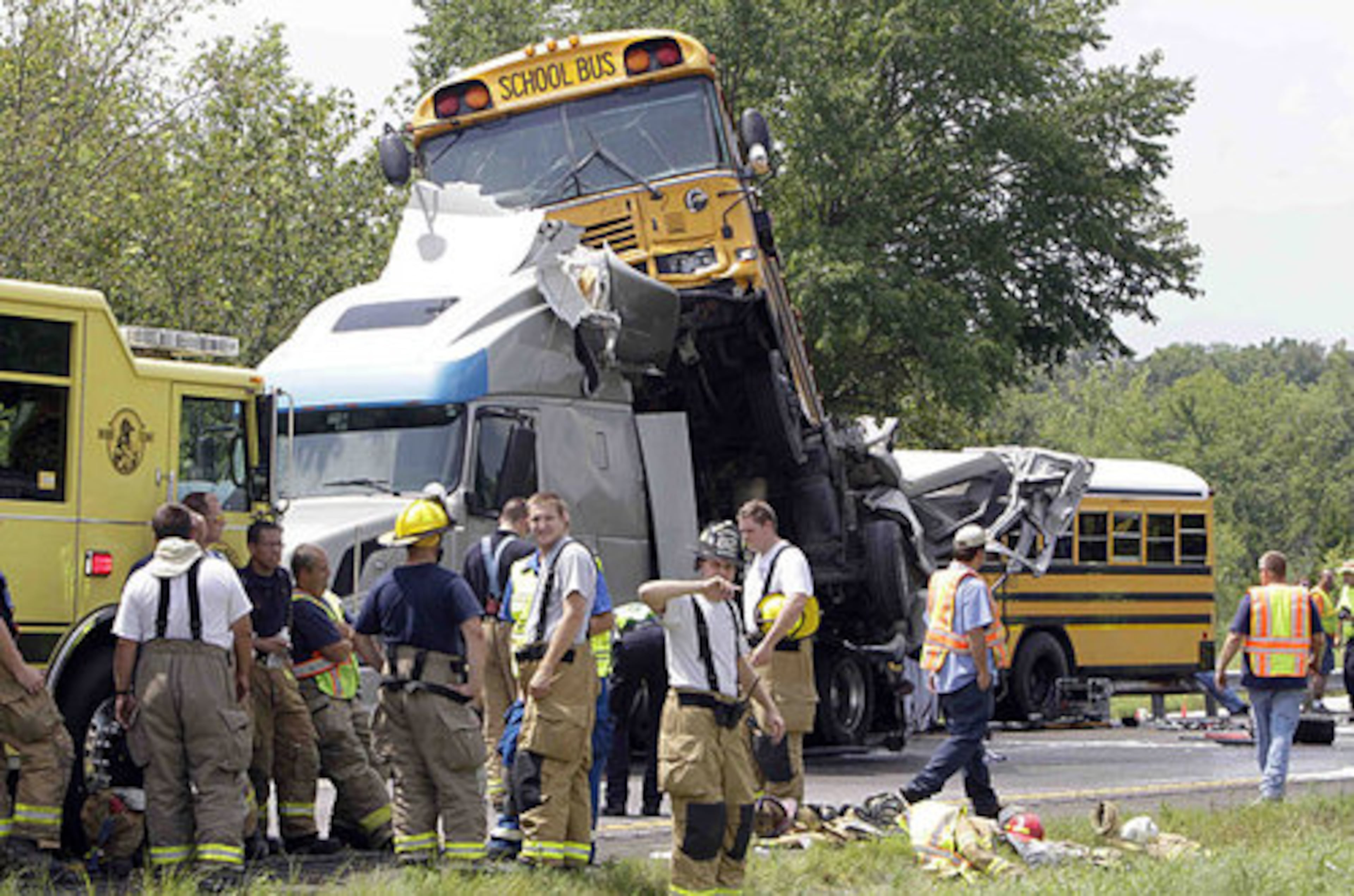 Rescue personnel work at the scene near Gray Summit, Mo. Vehicles involved in the crash included what appeared to be a sports utility vehicle, which was crushed and hardly distinguishable while wedged below the bus that came to rest atop the semi tractor's cab.