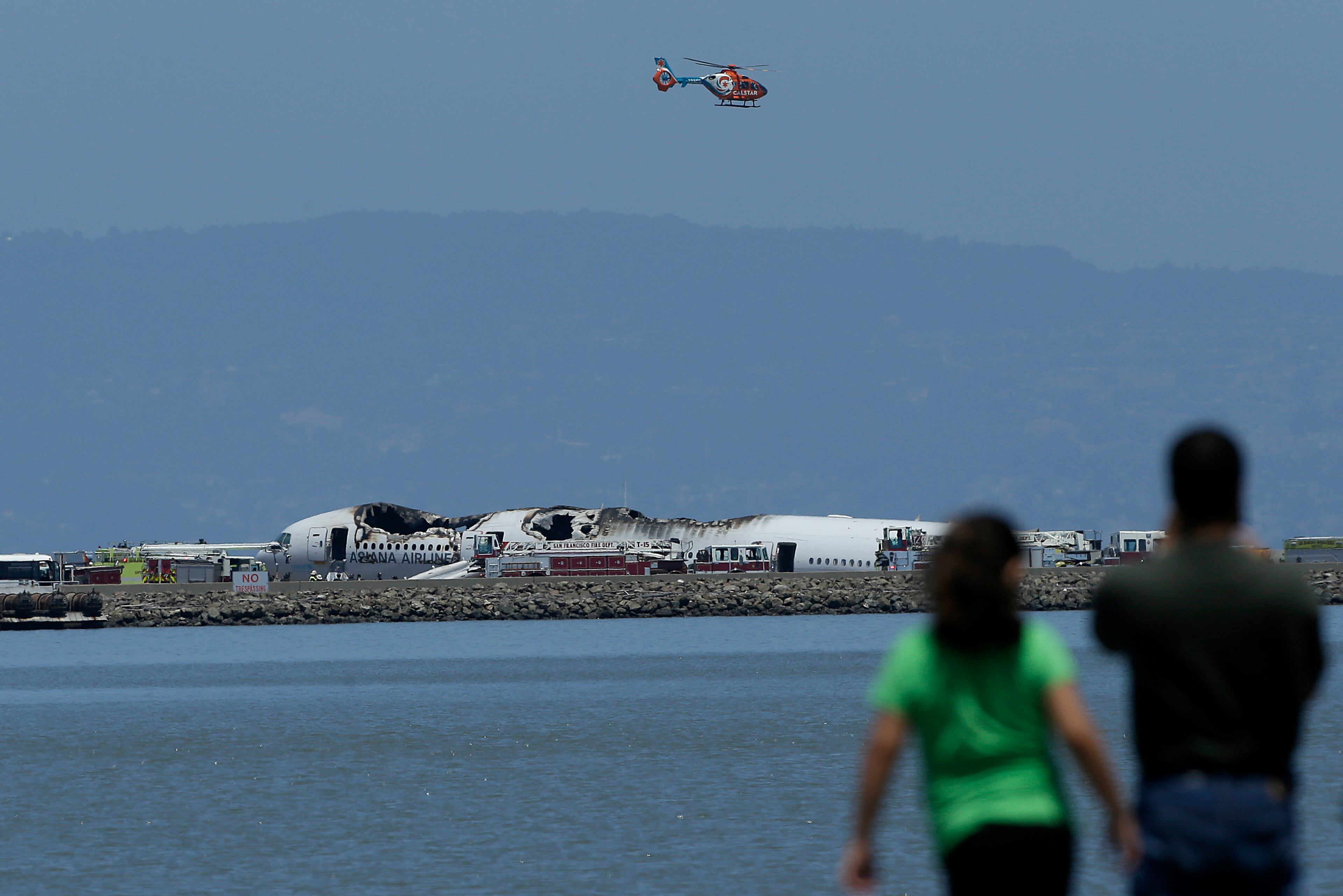 A helicopter flies above the wreckage of Asiana Flight 214 after it crashed at San Francisco International Airport in San Francisco, Saturday, July 6, 2013. (AP Photo/Jeff Chiu)
