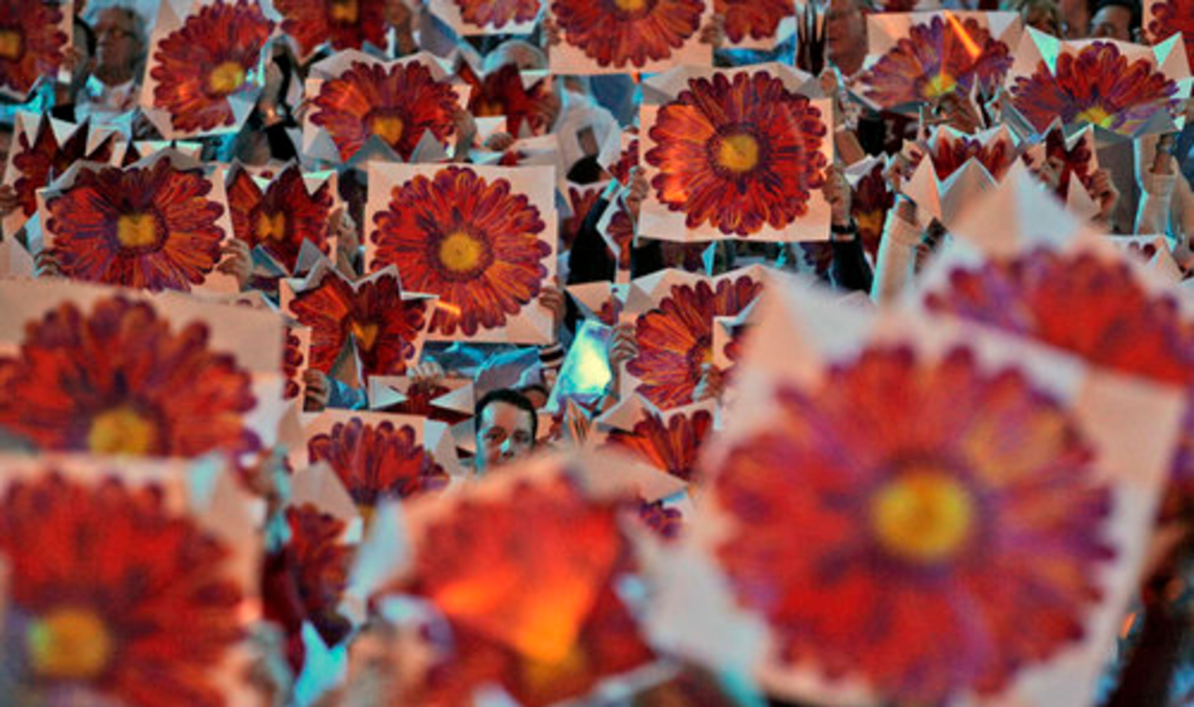 Performers hold boards with reflective flower prints on them during the closing ceremony.