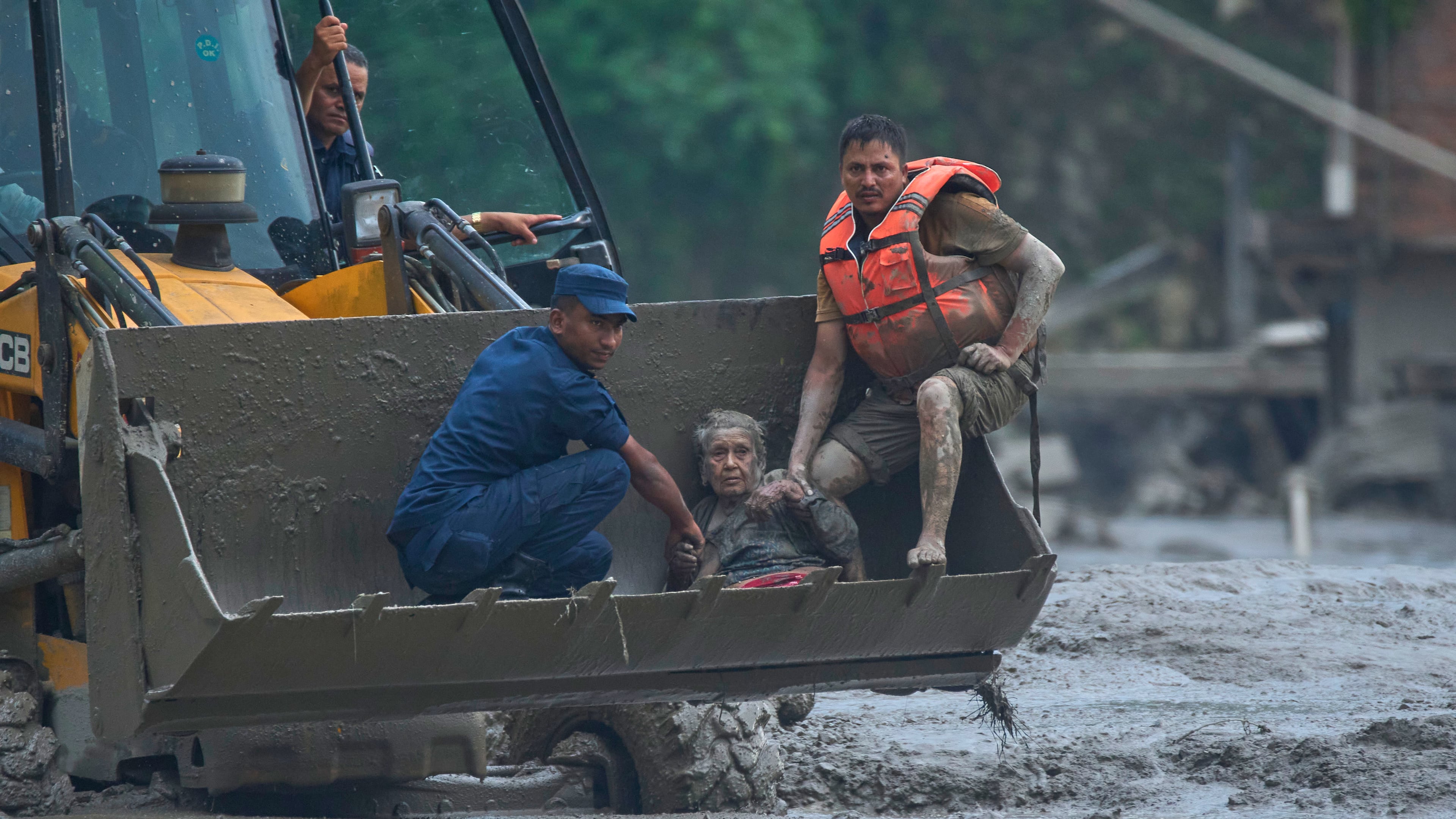 Rescuers use an earthmover to carry a victim of flash flooding to safety along the Trishuli River in Nepal's Nuwakot district, Wednesday, Aug. 26, 2026. (AP Photo/Niranjan Shrestha)