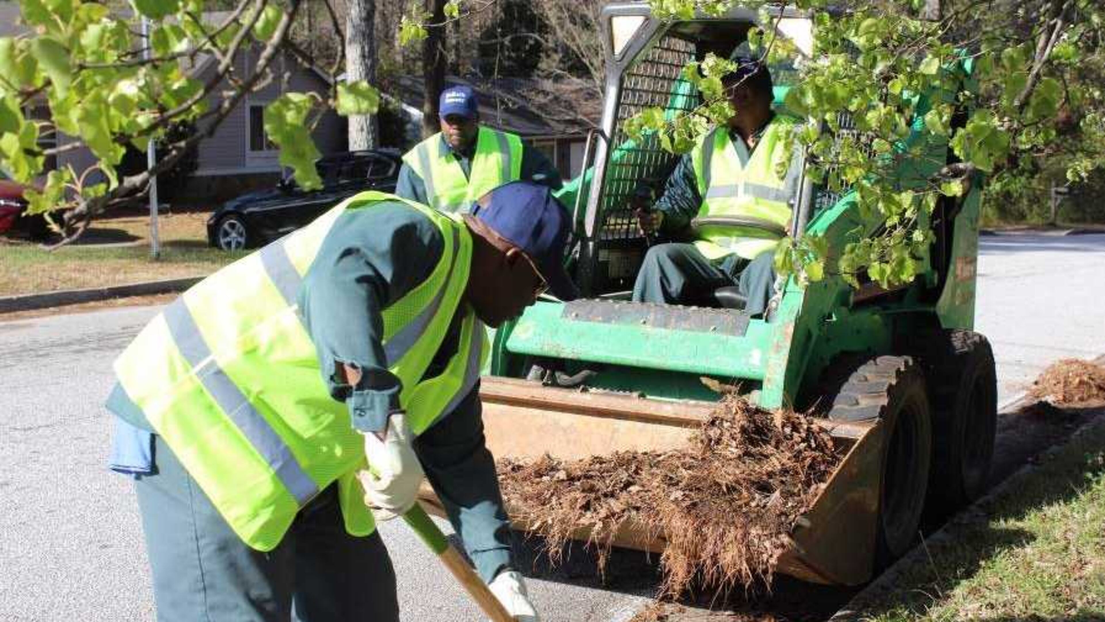 In areas too thick for a street sweeper to clean, crews manually dig debris to clear the curb. Photo via DeKalb County