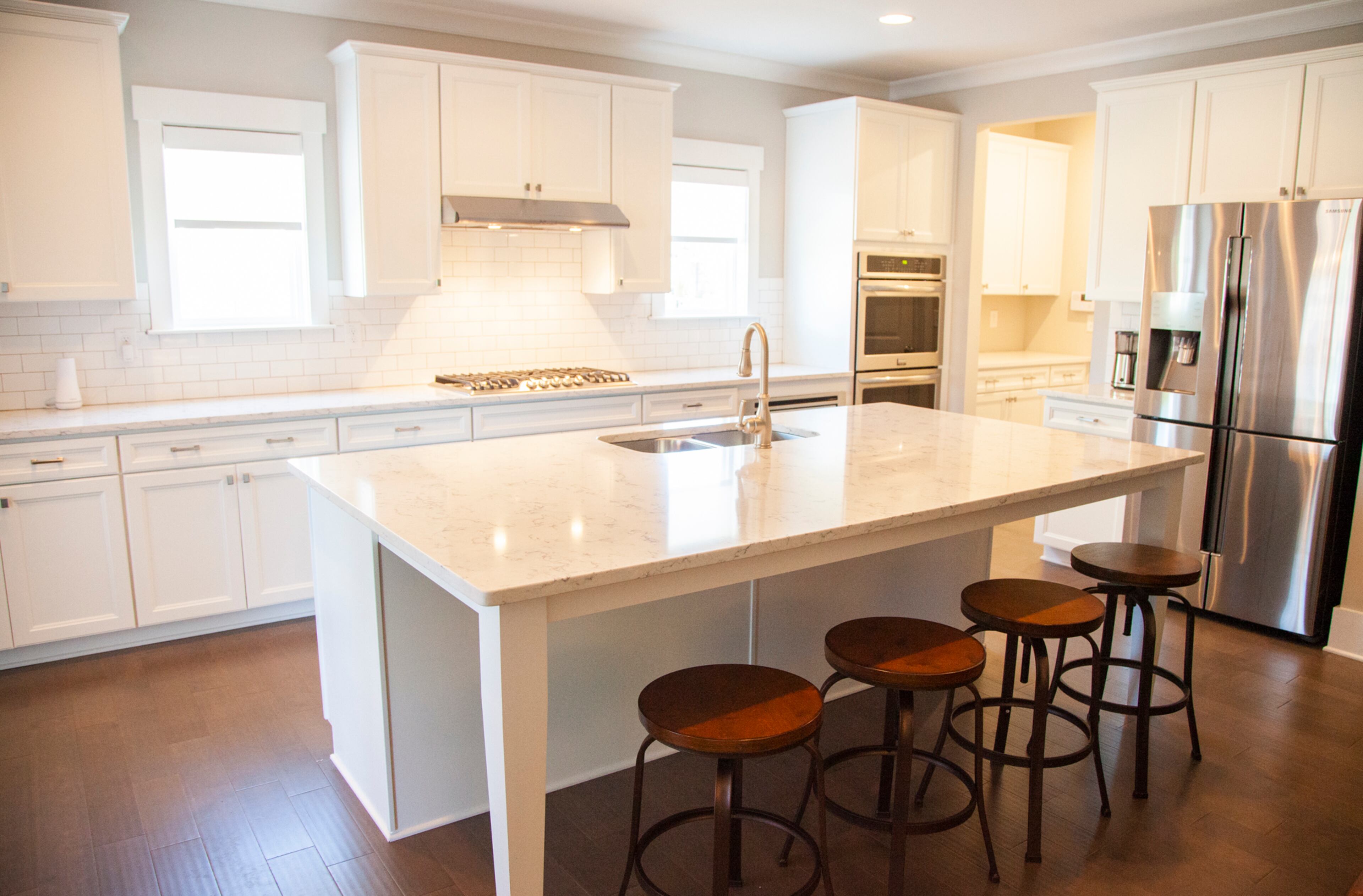 In the kitchen by Paran Homes, crisp whites and subway tiles give the space an airy, clean atmosphere. The appliances are from Frigidaire and the sink and faucet are from Moen.