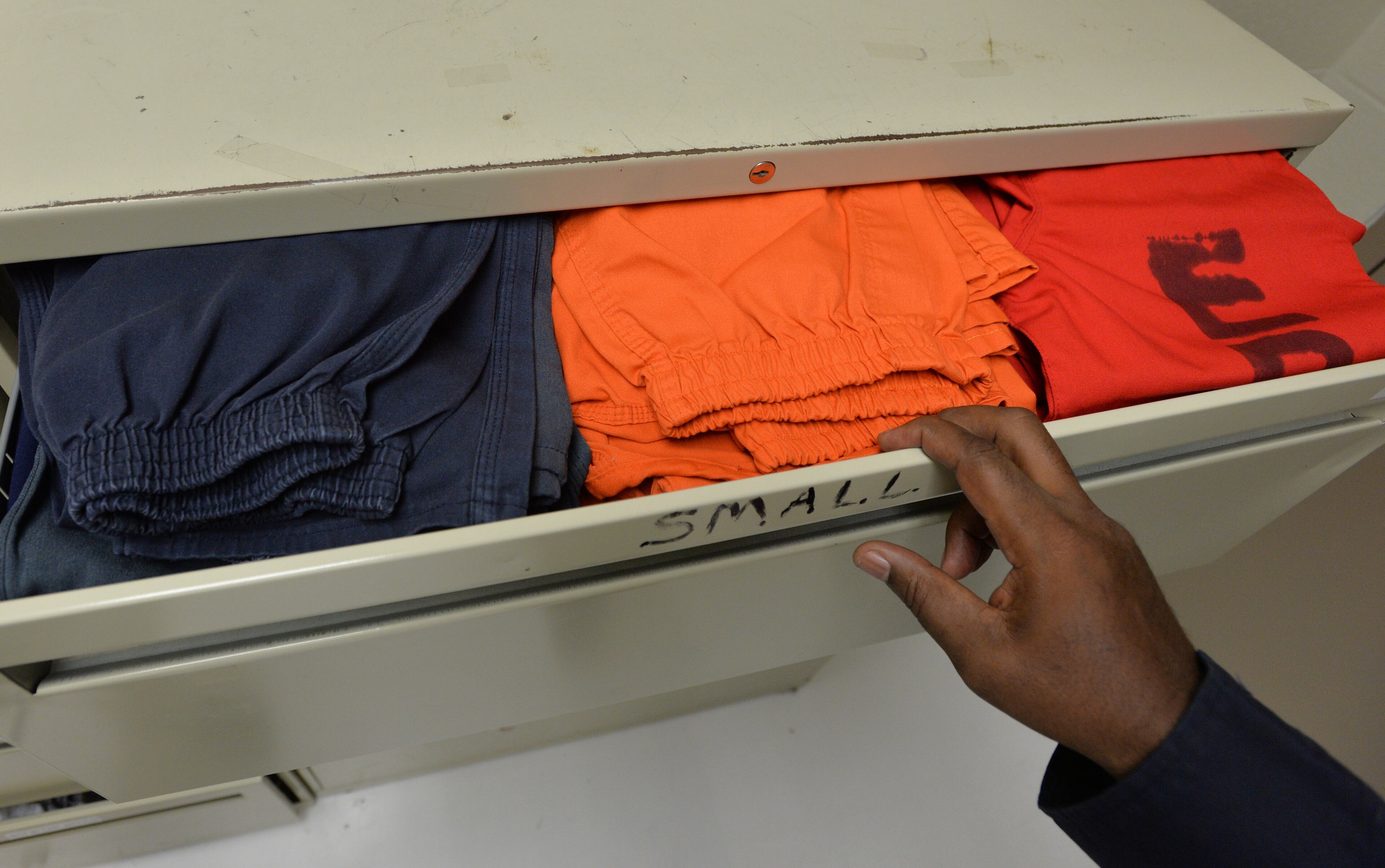 El Paso, Texas - Bernard Henderson, an ICE detention operations supervisor, shows different colored uniforms based on their criminal records at the El Paso Processing Center in El Paso, Texas on Friday, September 27, 2013. Red indicates they were convicted of serious crimes, such as murder, rape and robbery. Orange uniforms are for less serious offenders, including those who have committed theft or drug-related offenses. Those who have committed only immigration-related offenses wear dark blue. This bustling border city is both a gateway for illegal immigrants and the last stop many see before they are deported. Before they are expelled from the U.S., many illegal immigrants are held at the El Paso Processing Center, a razor wire-rimmed detention facility next to the city airport. HYOSUB SHIN / HSHIN@AJC.COM
