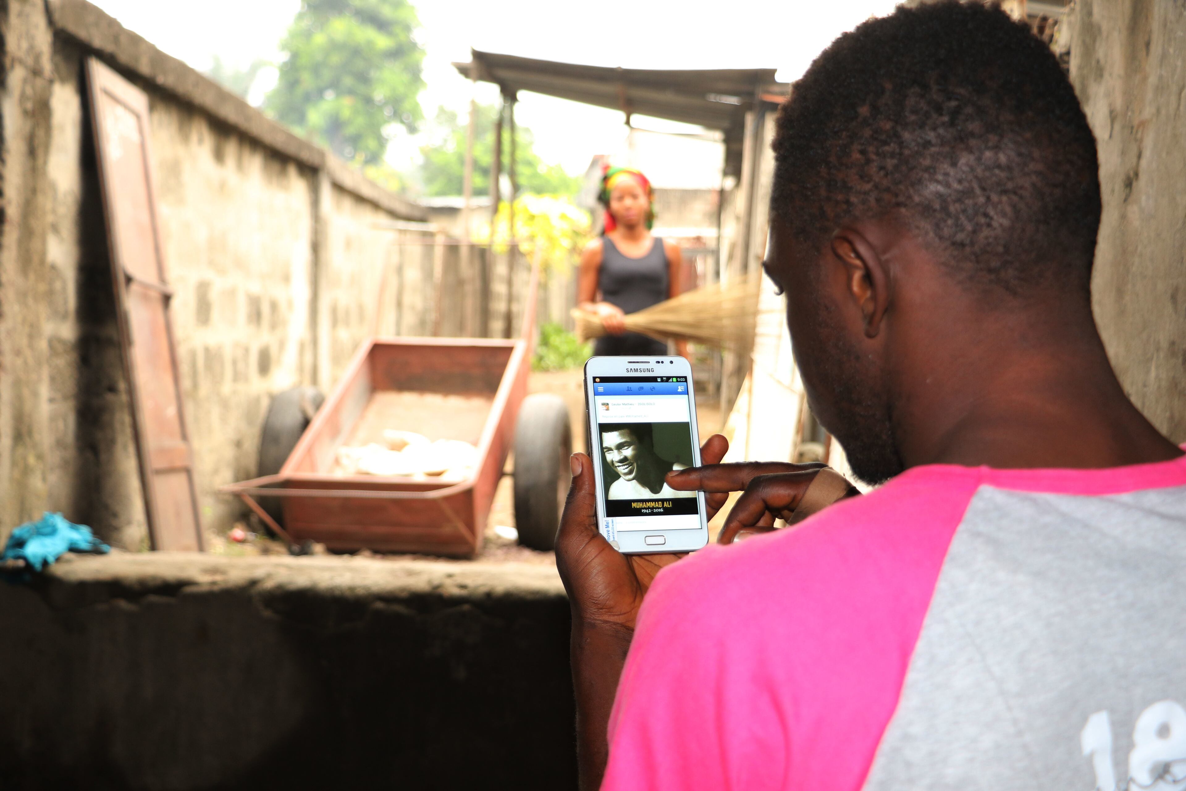 A man looks on the internet at a photo of heavyweight champion Muhammad Ali making use of his telephone in the city of Kinshasa, Congo, Saturday, June 4, 2016. Muhammad Ali rumbled in the African jungle, put on a thriller in Manila, charmed them in London and taunted them in Tokyo. (AP Photo/John Bompengo)
