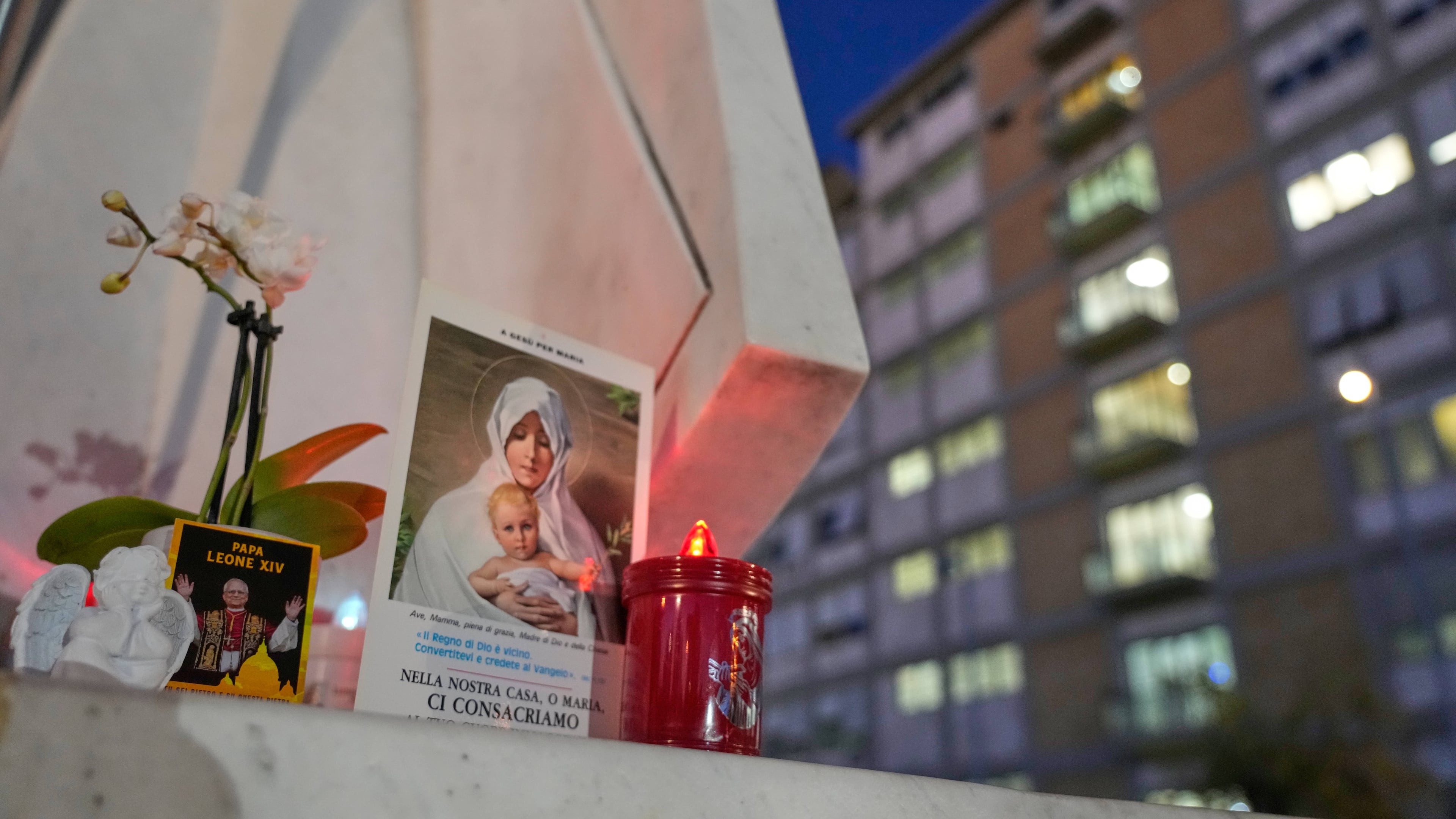 An image of Pope Leo XIV rests at the base of a statue of late pope St. John Paul II outside the Agostino Gemelli Polyclinic, where Leo is hospitalized for surgery to remove a lung nodule, in Rome, Tuesday, Oct. 13, 2026. (AP Photo/Gregorio Borgia)