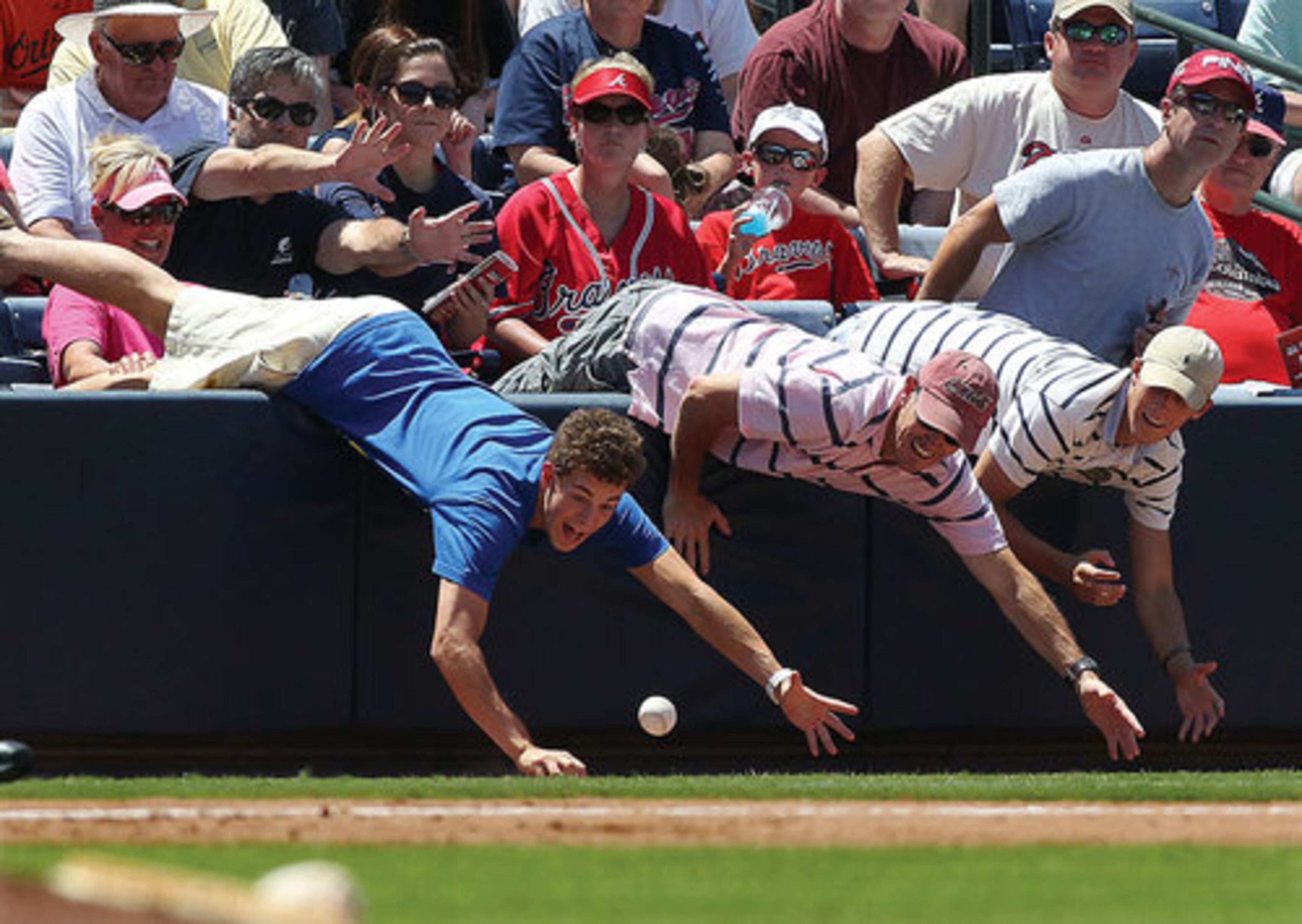 Baseball fans go over the wall to snag a foul ball by Atlanta Braves David Ross during the 5th inning.