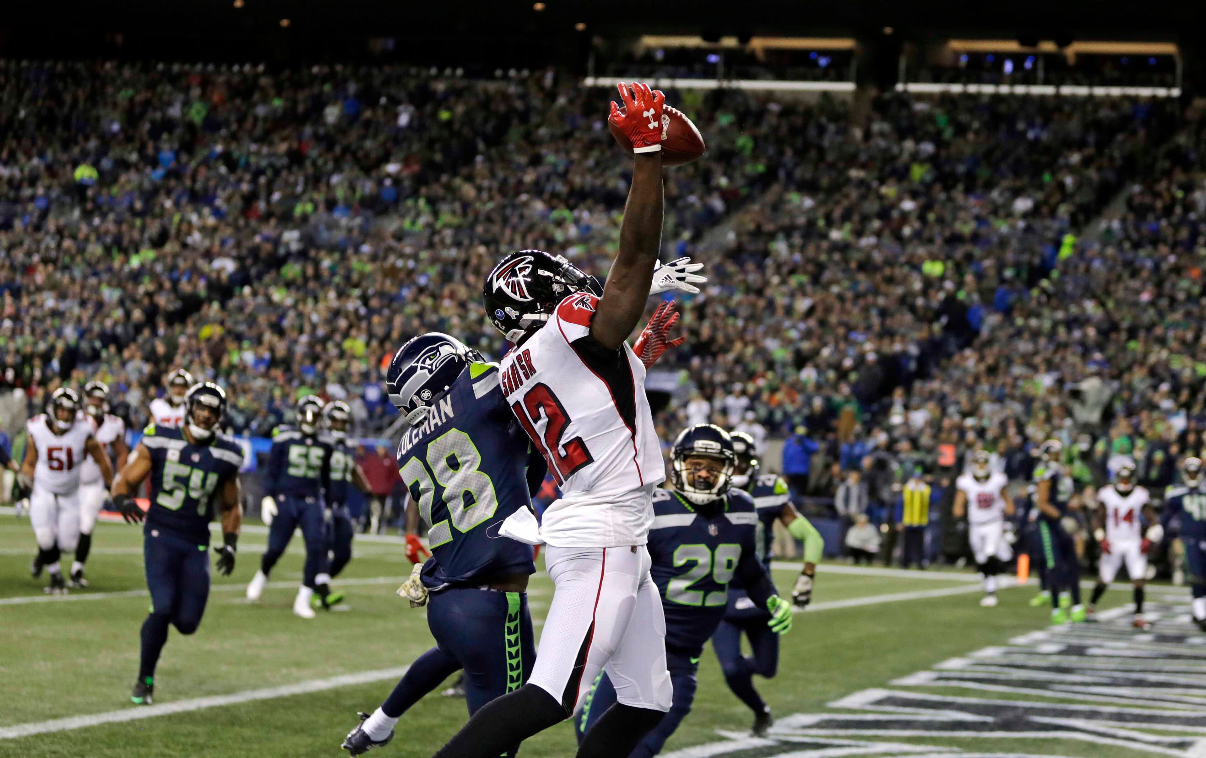 Atlanta Falcons' Mohamed Sanu (12) reaches to snag the ball for a touchdown on a pass reception as Seattle Seahawks' Justin Coleman defends in the first half of an NFL football game, Monday, Nov. 20, 2017, in Seattle. (AP Photo/Stephen Brashear)
