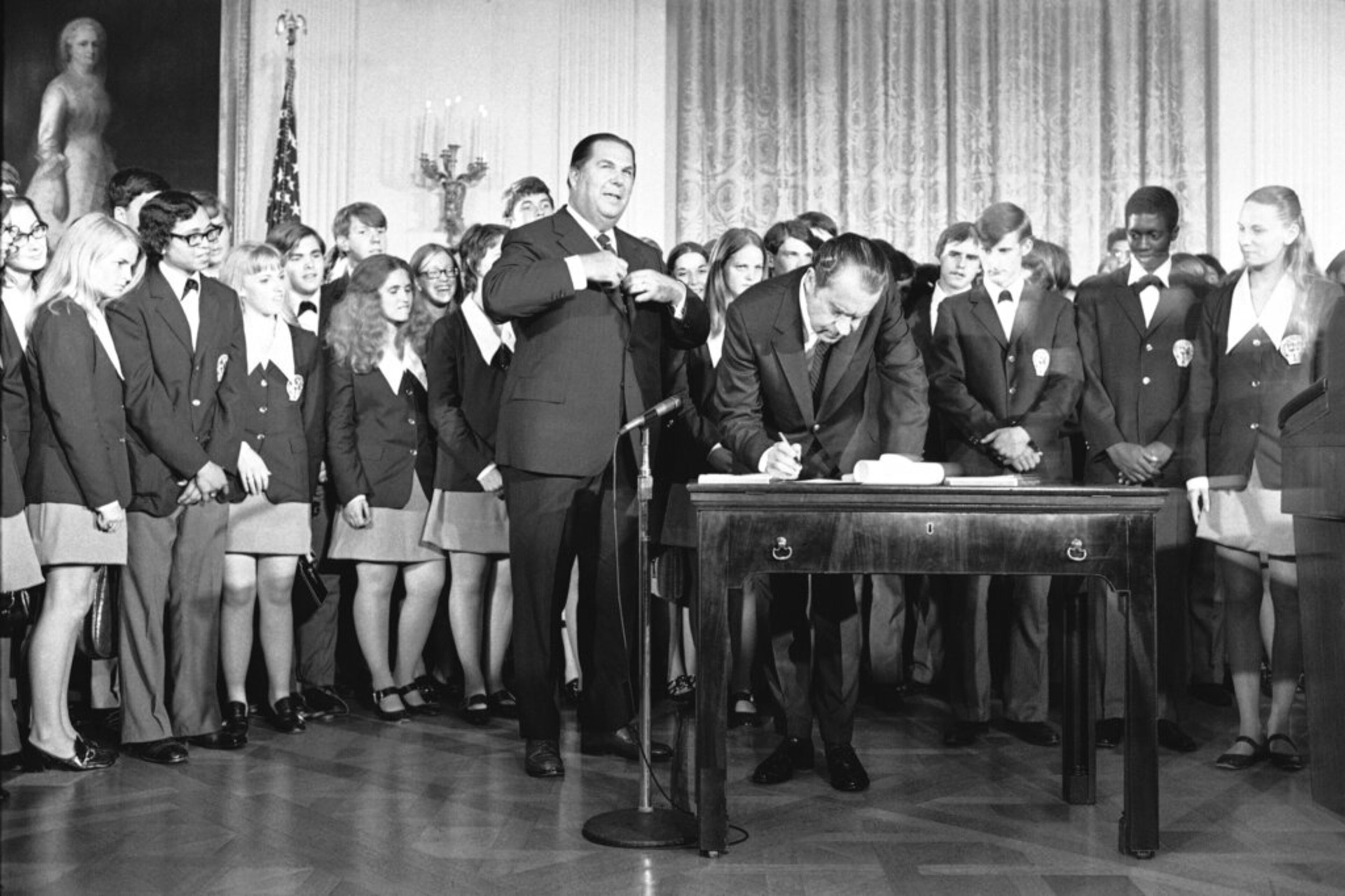 FILE - In this July 4, 1971 file photo, President Richard Nixon signs the Constitution's newest amendment which guarantees 18-year-olds the right to vote in all elections. Robert Kunzig, general services administrator, waits to certify officially ratification of the 26th amendment. The signing took place in East Room of the White House in Washington. Paul Larimer of Concord, Calif. , a member of the singing group "Young Americans" also signed the amendment. (AP Photo/Charles Tasnadi)