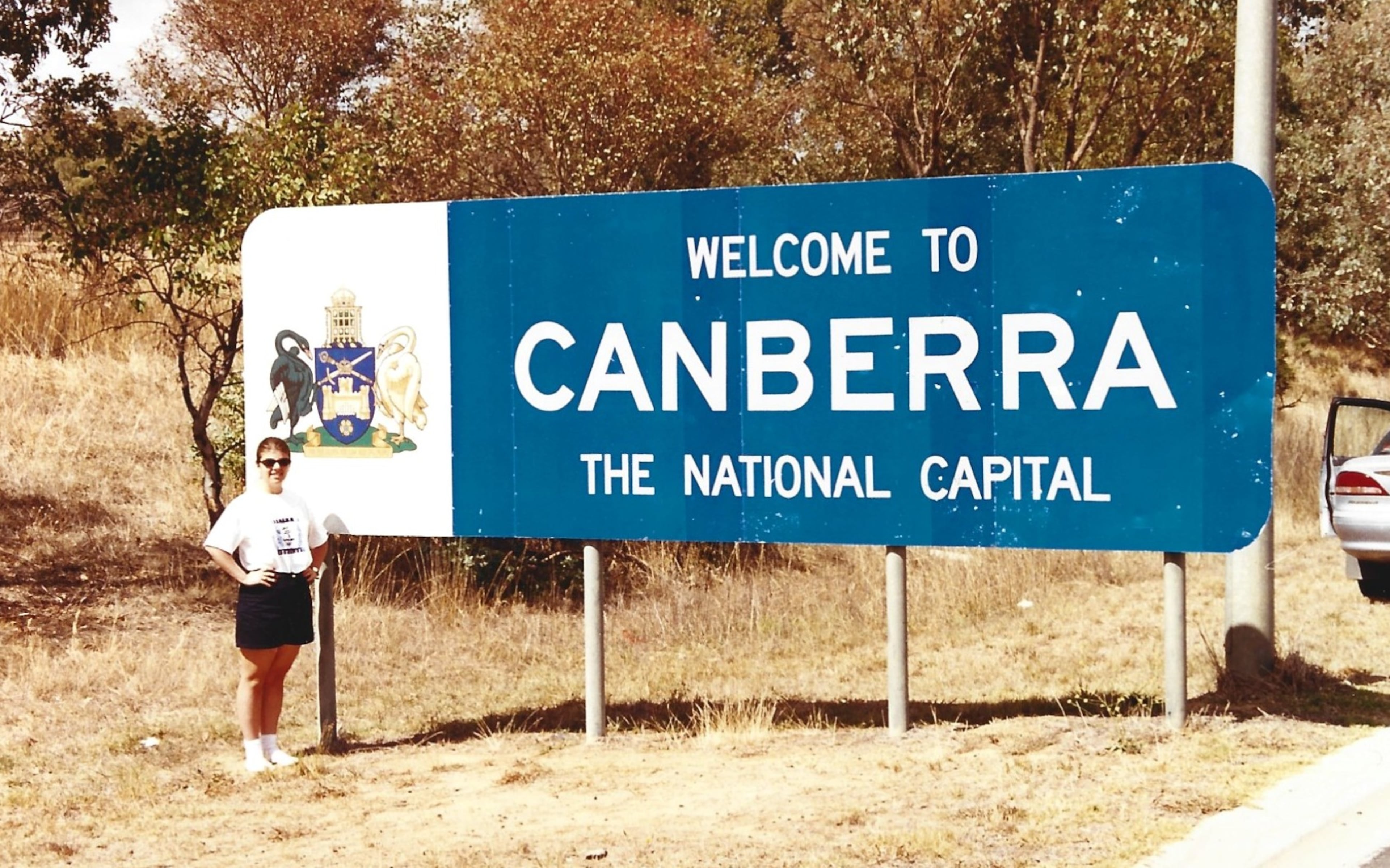 Heather poses in front of a sign welcoming visitors to Canberra, Australia's capital city. (Courtesy of Steve Leo)
