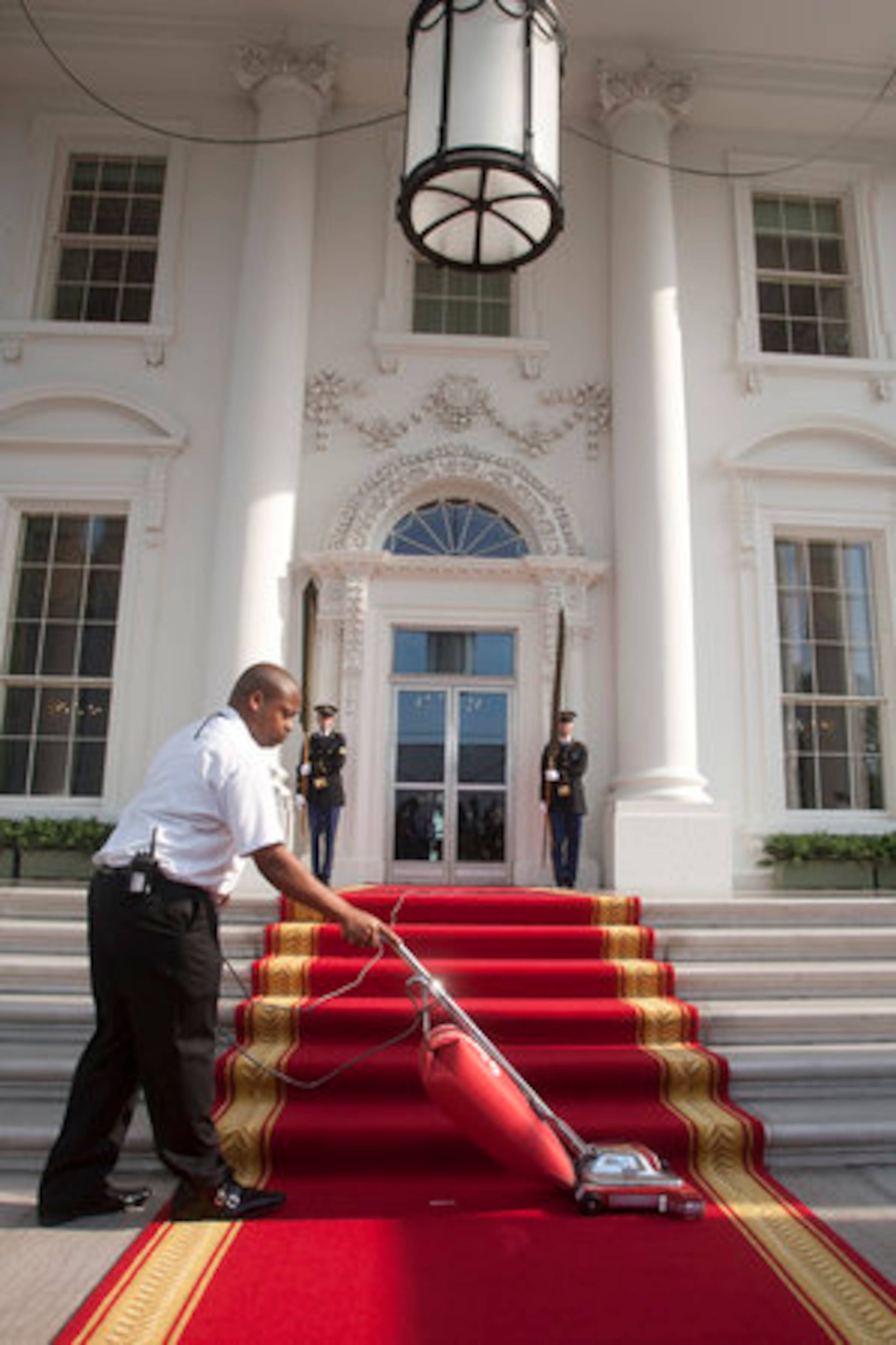 A man vacuums the red carpet on the North Portico of the White House before the arrival of Angela Merkel, Germany's chancellor, in Washington, D.C., U.S., on Tuesday, June 7, 2011. U.S. President Barack Obama said he and Merkel agreed that the debt crisis in Europe "cannot be allowed to put the global economic recovery at risk."