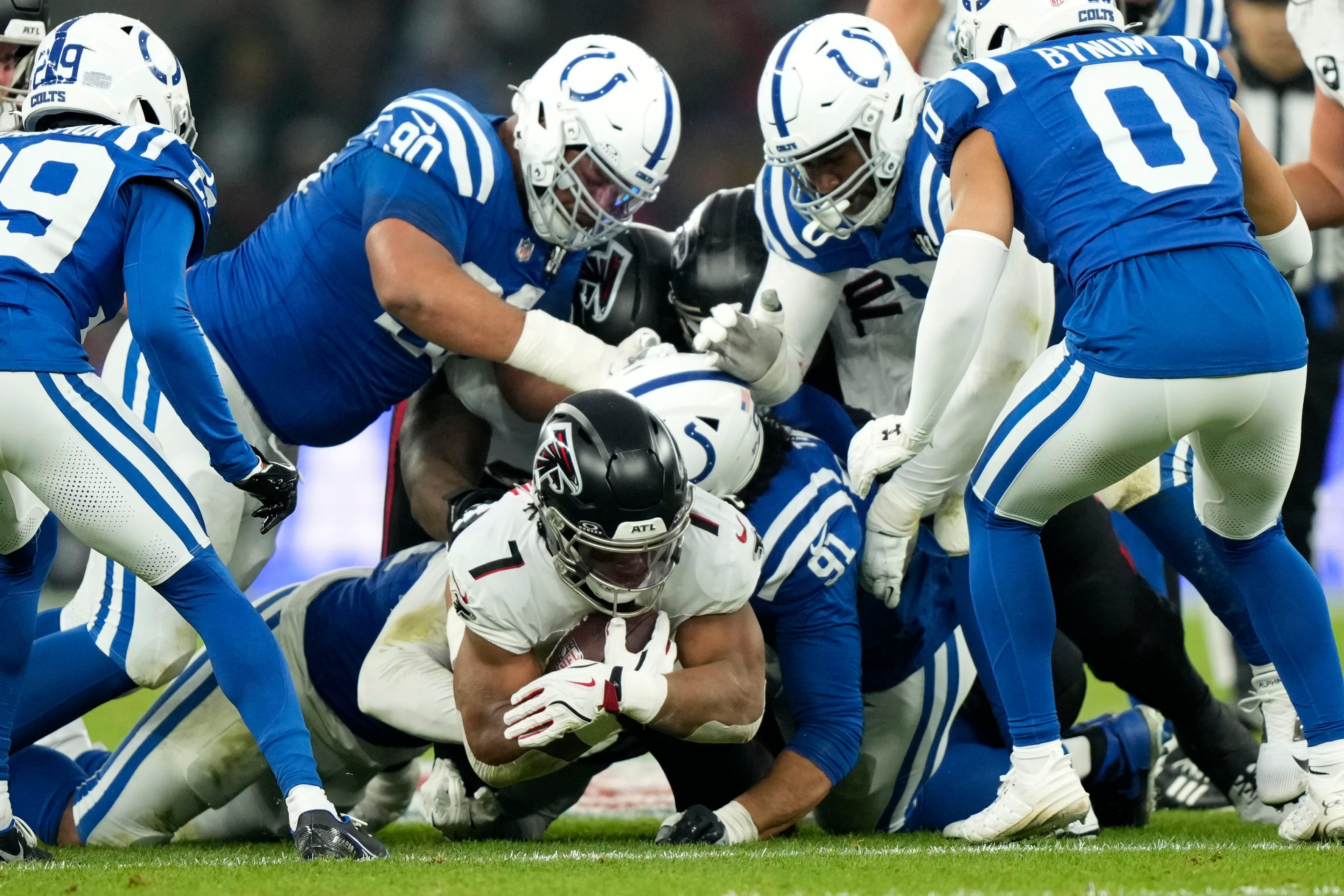 Atlanta Falcons running back Bijan Robinson (7) is tackled by Indianapolis Colts defensive end JT Tuimoloau (91) during the first half of an NFL football game, Sunday, Nov. 9, 2025, in Berlin, Germany. (AP Photo/Ebrahim Noorozi)