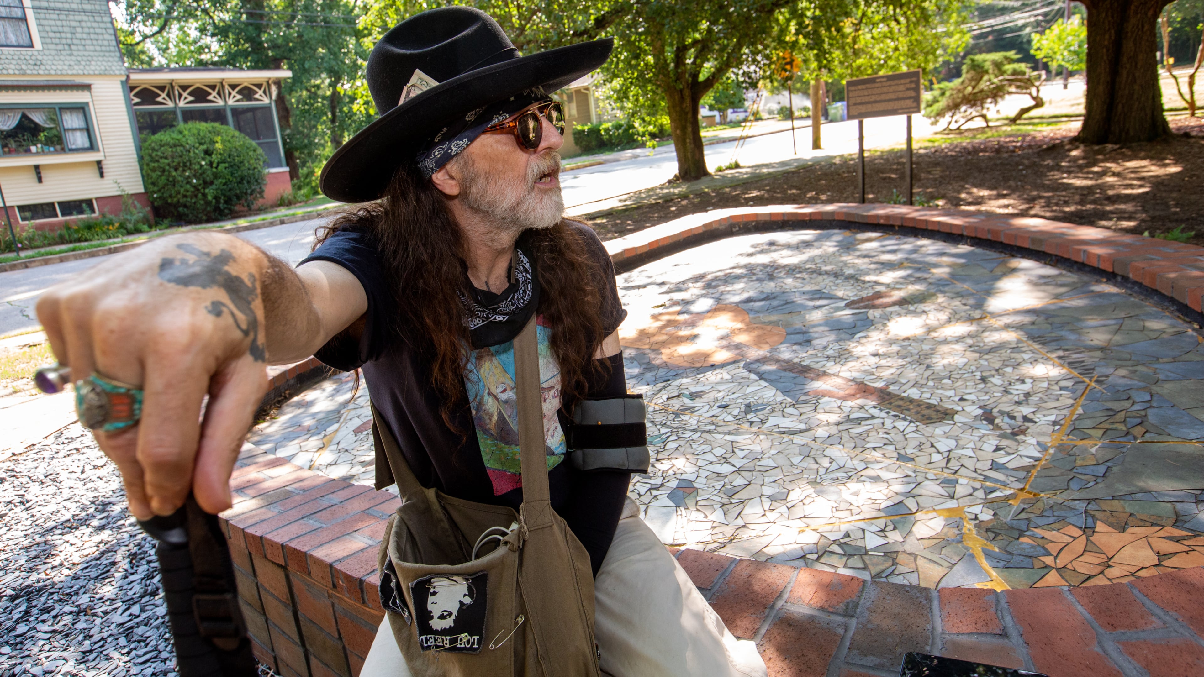 Artist Jason Evers Johnson sits at the foot of his monumental mosaic portrait of blues legend Blind Willie McTell. When the mosaic was threatened by redevelopment, Johnson returned to Atlanta from his home in Italy, to oversee its removal, in pieces, and its reconstruction, outside the Little Five Points Community Center. After the re-assembly was complete, the piece was modified without Johnson's knowledge. (Jenni Girtman for The Atlanta Journal-Constitution)