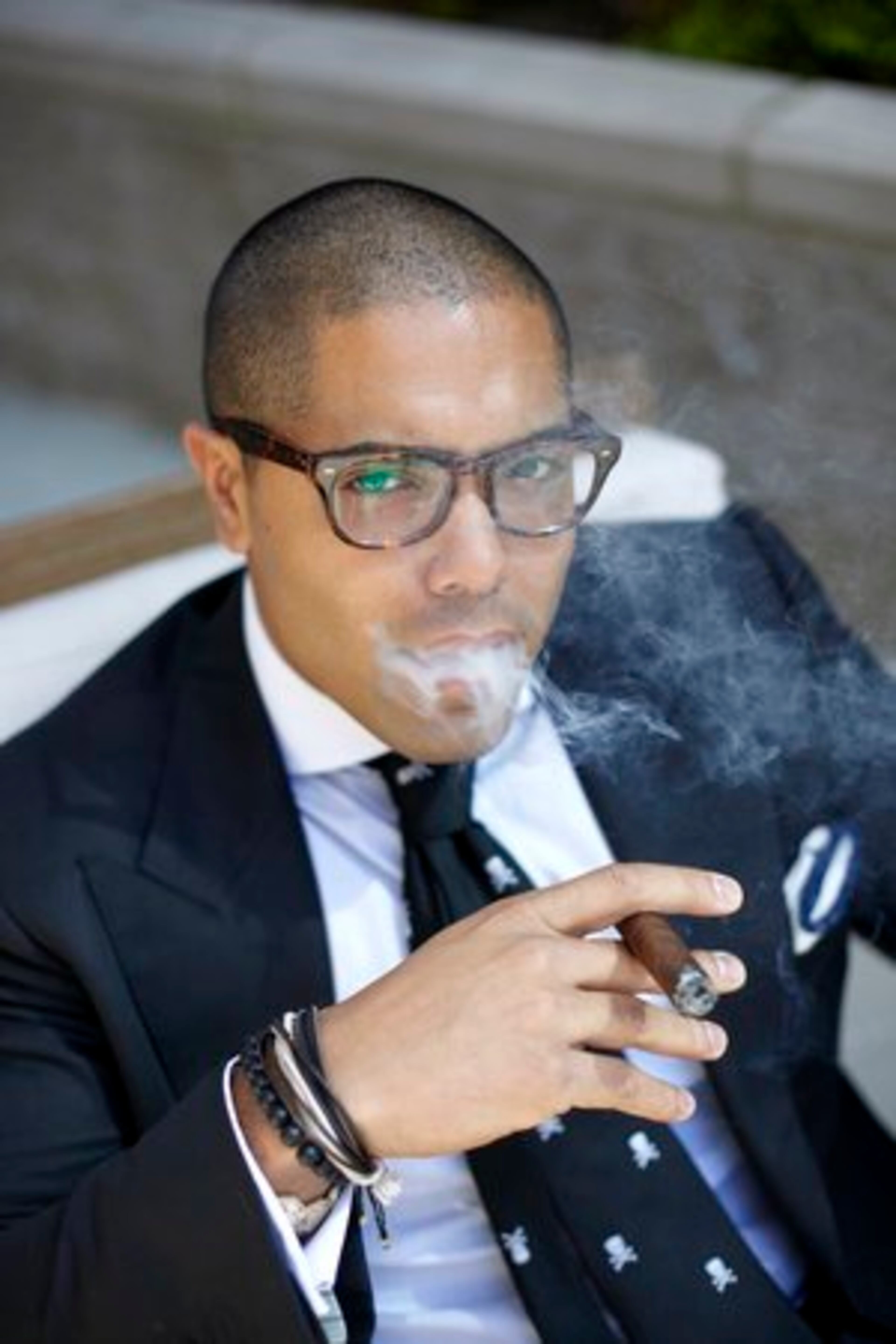 Ramos, in his custom-made Astor & Black suit and tie, regularly enjoys smoking cigars, which remind him of time spent with his grandfather.