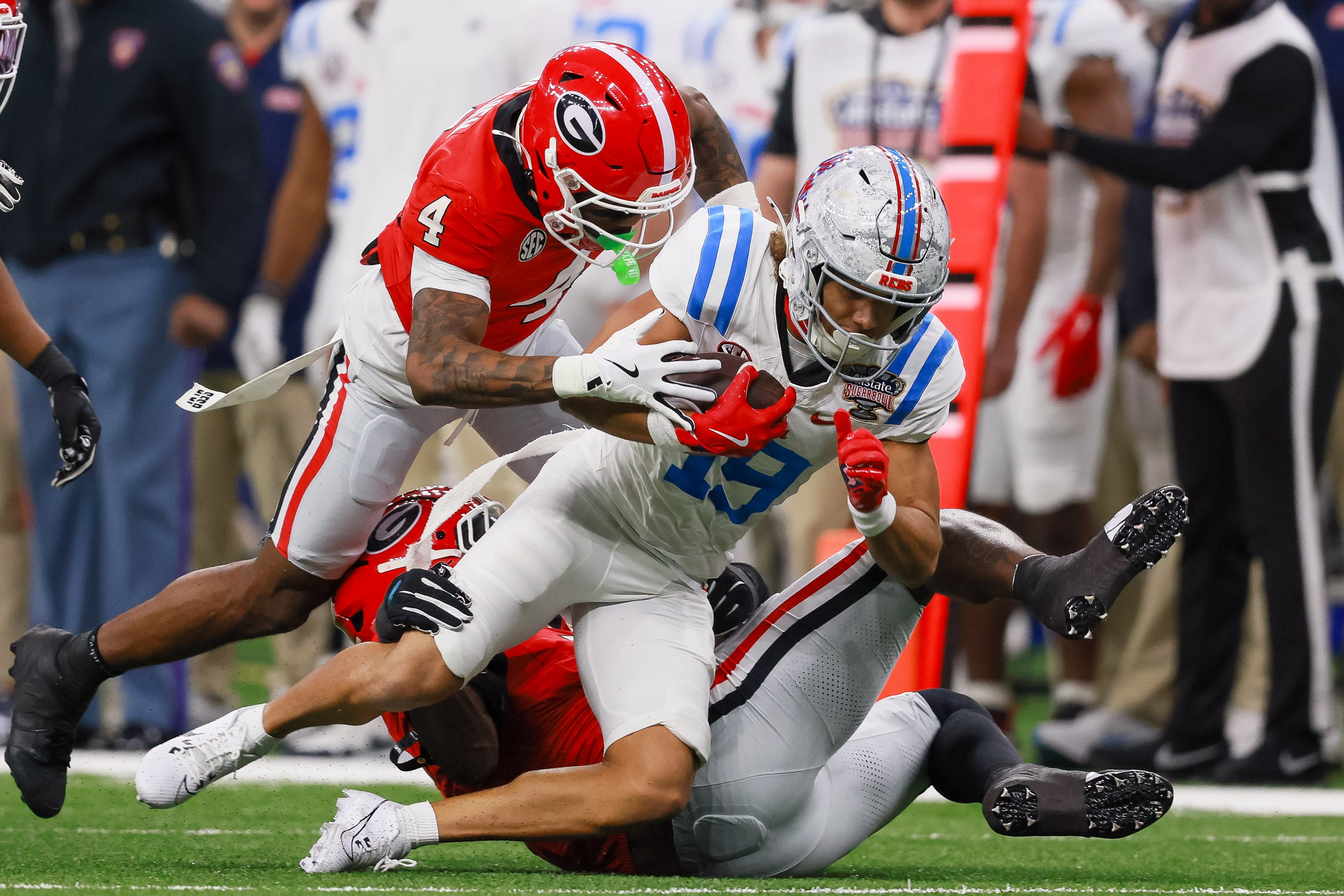 Georgia Bulldogs defensive back KJ Bolden (left) tackles Ole Miss Rebels wide receiver Cayden Lee (center) during the first quarter of the Georgia vs. Ole Miss NCAA College Football Playoff quarterfinal game at the Sugar Bowl in the Caesars Superdome, Thursday, Jan. 1, 2026, in New Orleans. (Jason Getz/AJC)