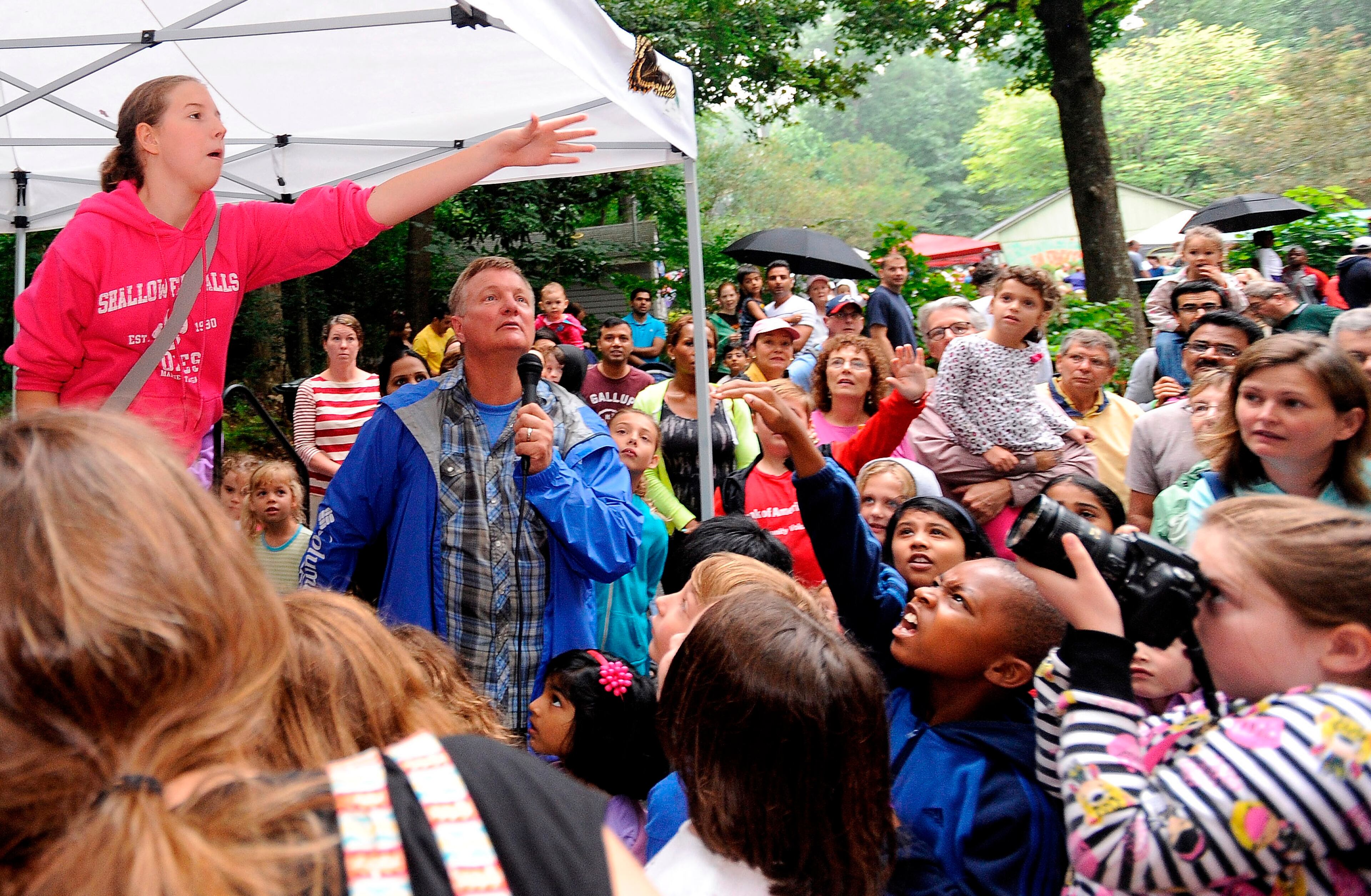 A participant releases a butterfly as it soars away over butterfly expert Zane Greathouse, center, and several hundred attending the Dunwoody Nature Center Butterfly Festival on Aug. 17, 2013, in Dunwoody.