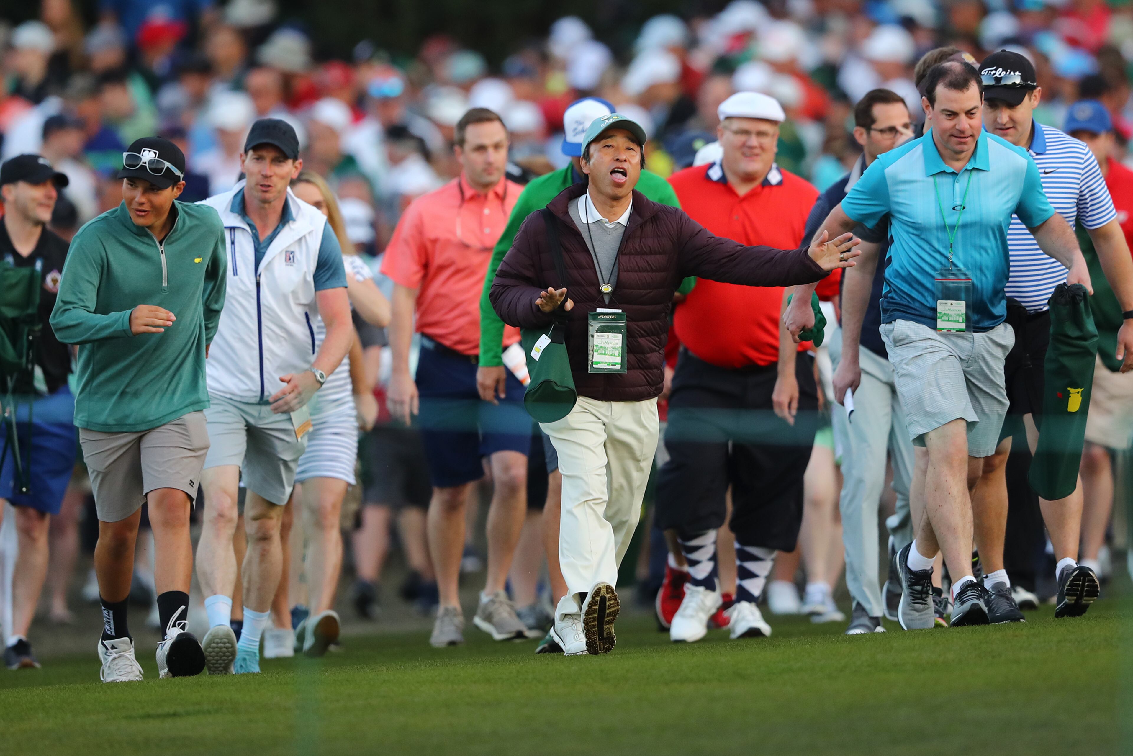 Patrons speed walk up the hill as the gates to the golf course open to watch honorary starters Jack Nicklaus and Gary Player tee off on the first hole. (Curtis Compton/ccompton@ajc.com)