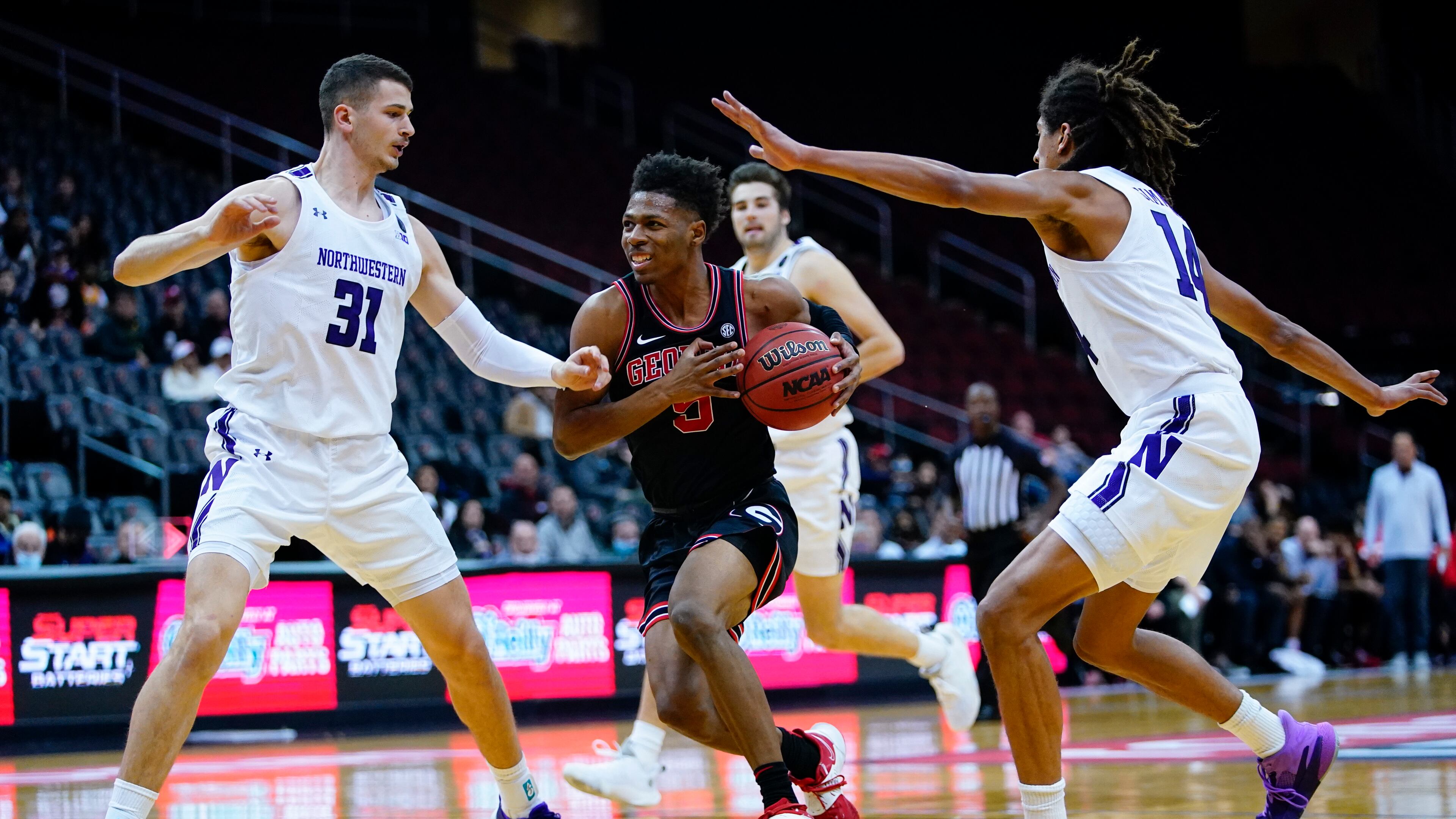 Georgia's Christian Wright (5) drives past Northwestern's Robbie Beran (31) and Casey Simmons (14) during the first half of an NCAA college basketball game Tuesday, Nov. 23, 2021, in Newark, N.J. (AP Photo/Frank Franklin II)