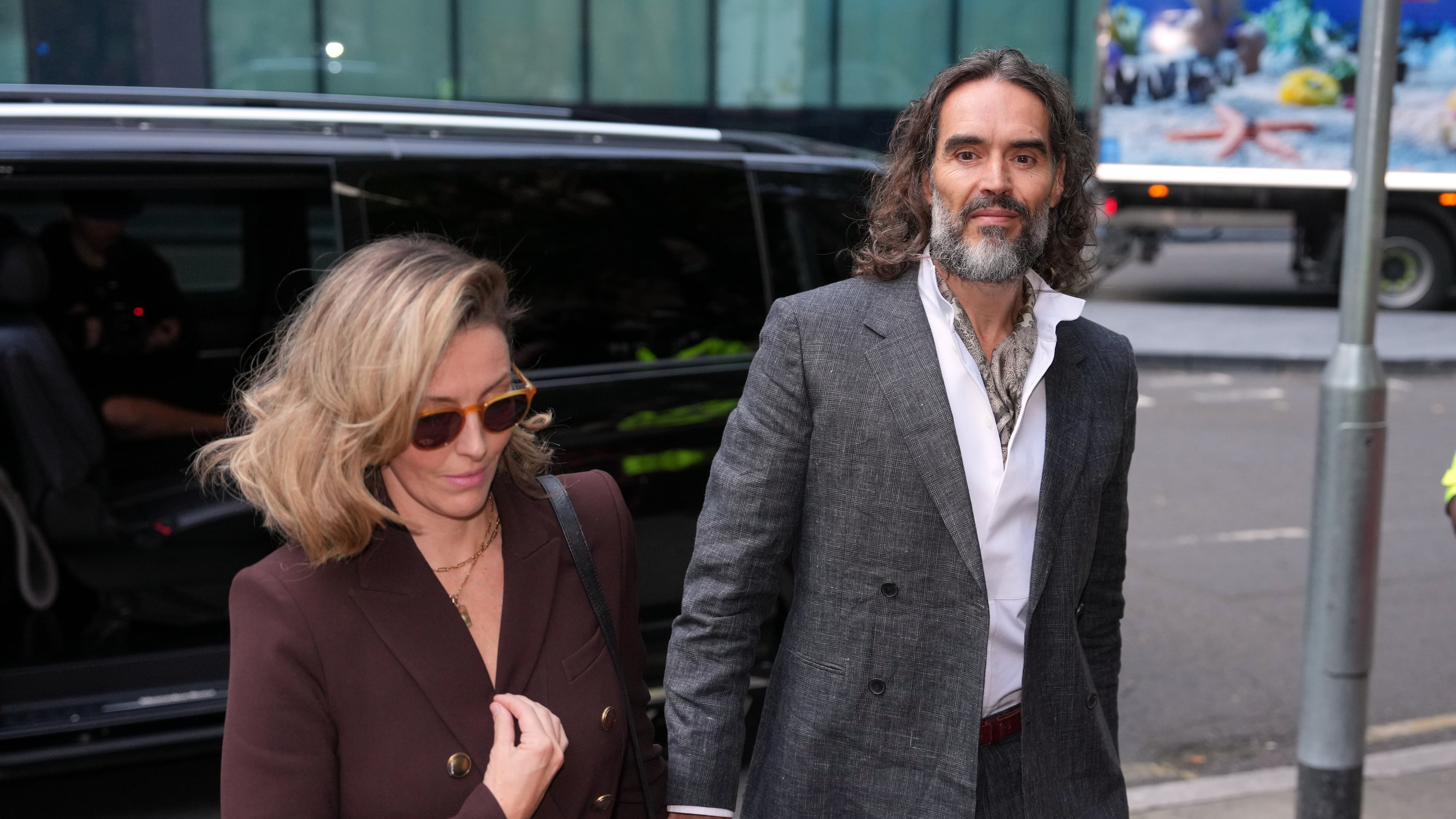 Comedian and actor Russell Brand, accompanied by his wife Laura Brand, arrives at Southwark Crown Court where he is charged with counts of rape and sexual assault against six women, which he has denied, in London, Monday, Oct. 12, 2026.(AP Photo/Kin Cheung)