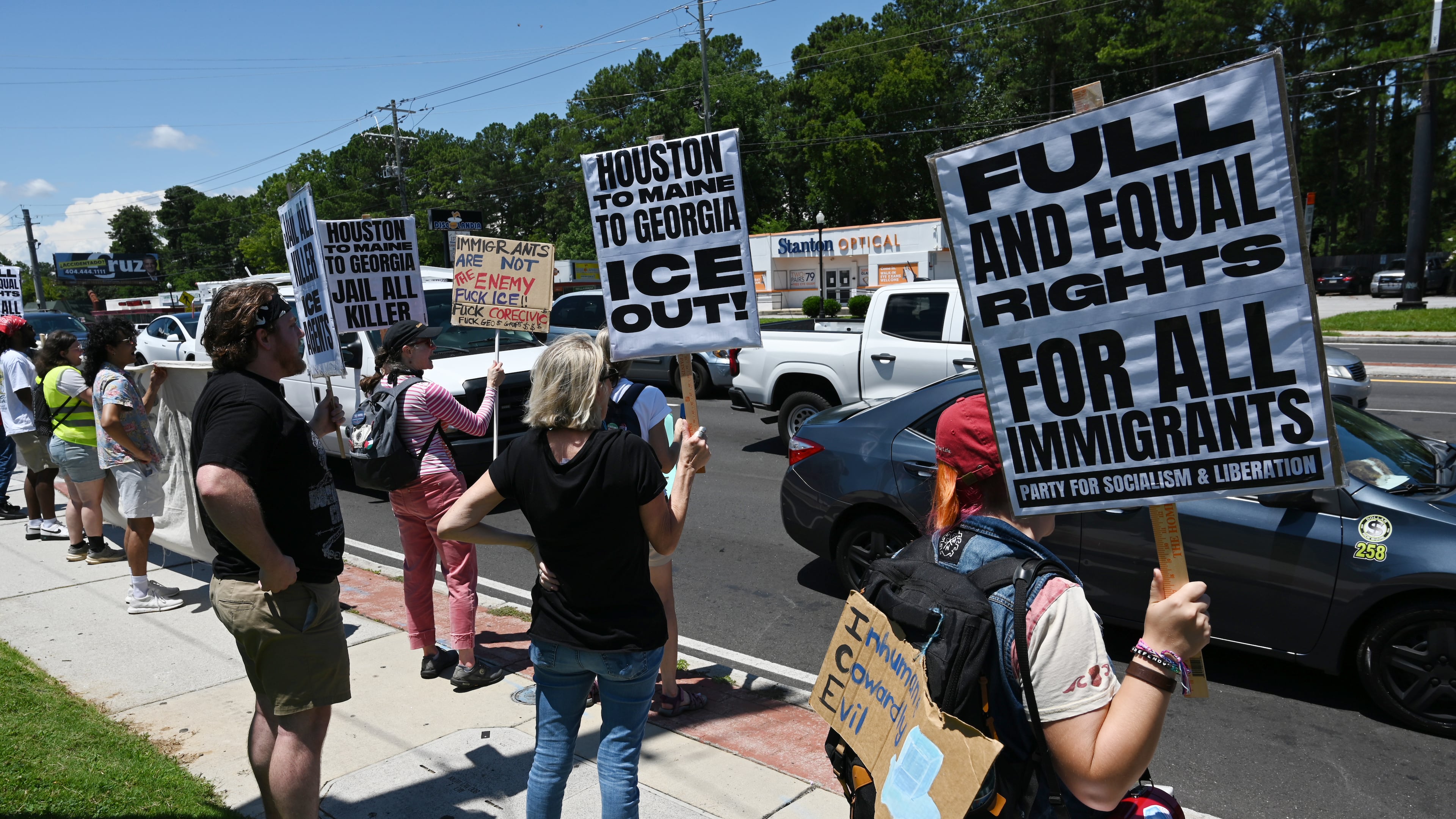 Over two dozen demonstrators gathered at the corner of Buford Highway and Briarwood Road to protest recent ICE raids as part of a nationwide Day of Action on Saturday, July 18, 2026, in Atlanta. (Hyosub Shin/AJC)