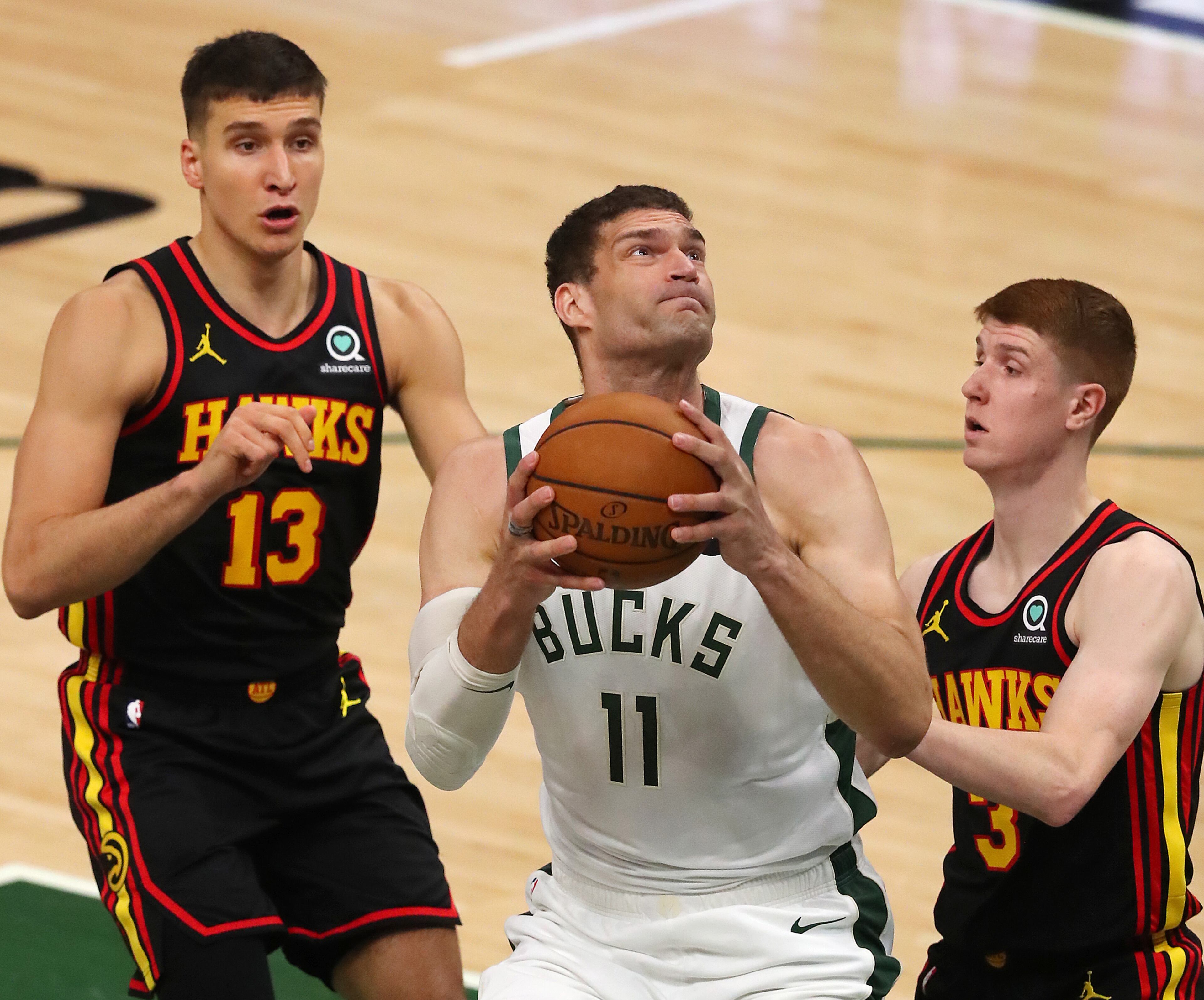 Hawks guards Bogdan Bogdanovic (left) and Kevin Huerter can't stop Milwaukee Bucks center Brook Lopez from going to the basket for two of his 33 points during the first quarter in game 5 of the NBA Eastern Conference Finals on Thursday, July 1, 2021, in Milwaukee. “Curtis Compton / Curtis.Compton@ajc.com”