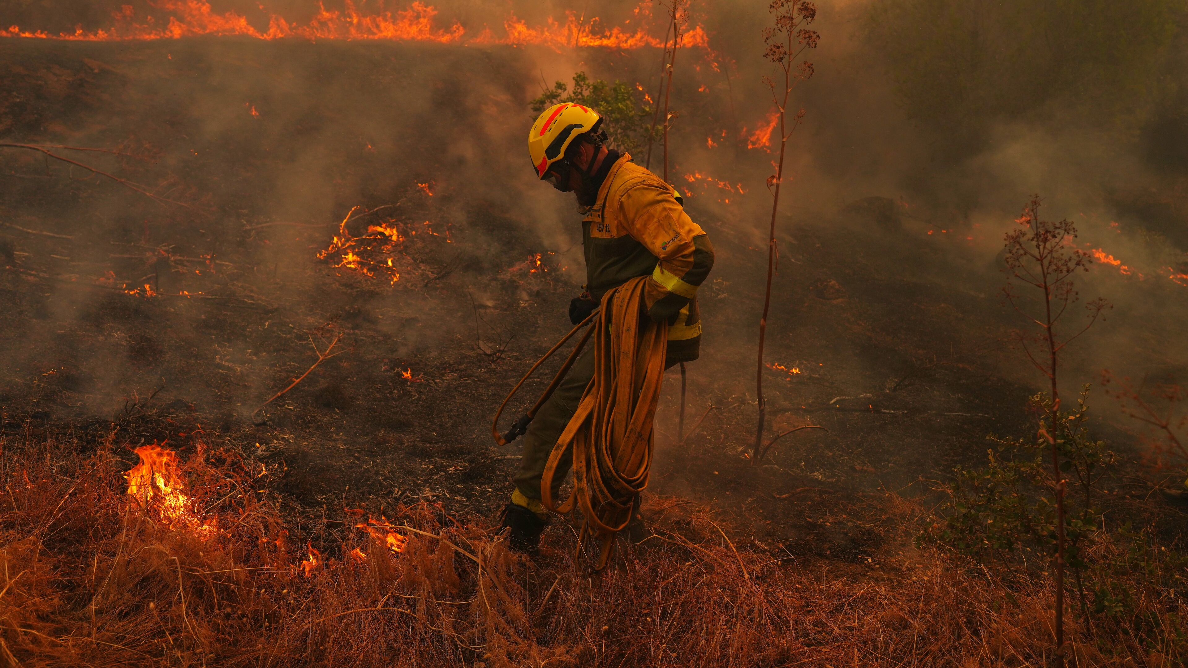 FILE - A firefighter carries a hose while battling a wildfire in San Martin de Valdeiglesias, west of Madrid, Spain, July 26, 2026. (AP Photo/Manu Fernandez, File)