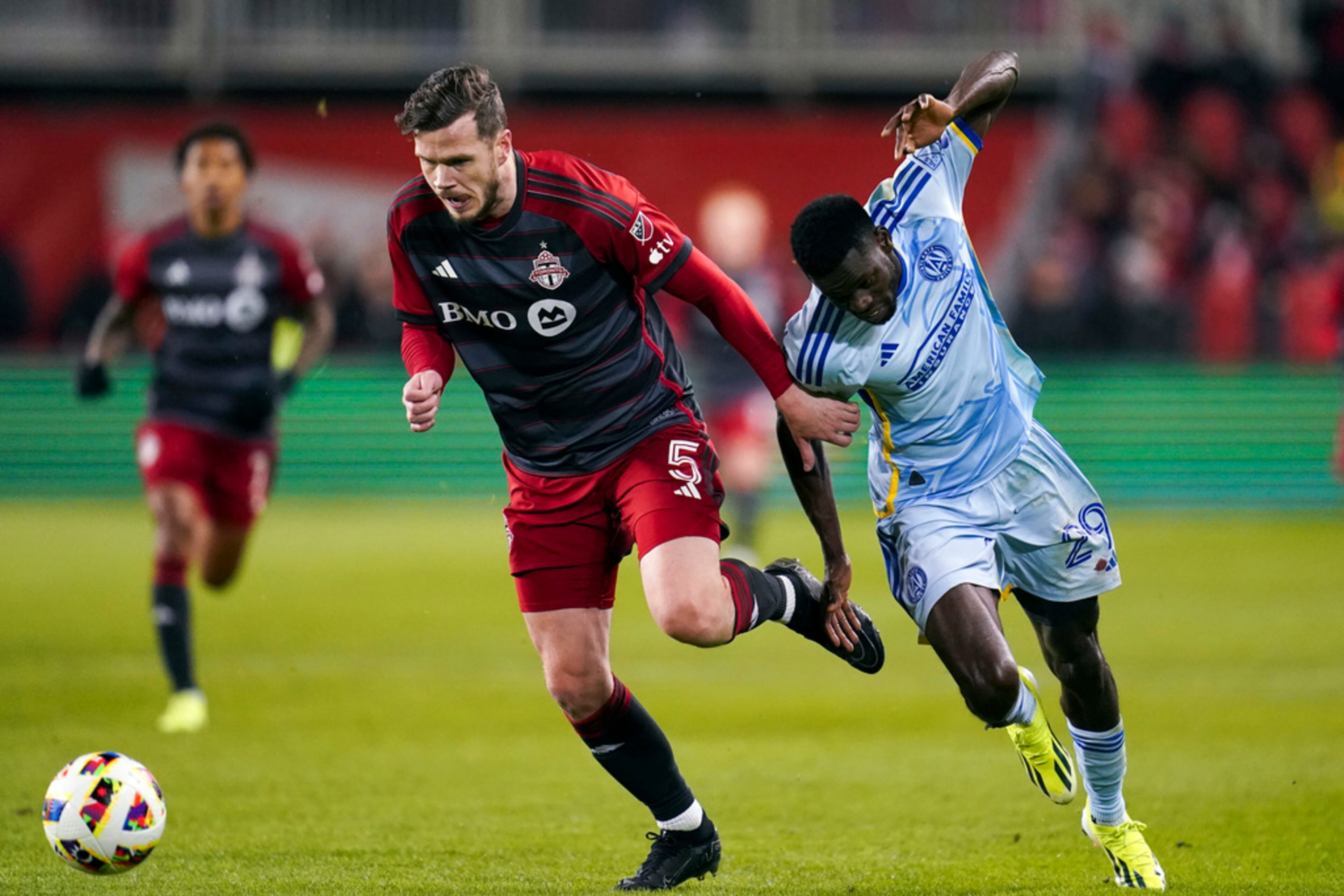 Toronto FC defender Kevin Long (5) runs after the ball while being chased by Atlanta United forward Jamal Thiare (29) during the first half of a MLS soccer match in Toronto on Saturday, March 23, 2024. (Arlyn McAdorey/The Canadian Press via AP)