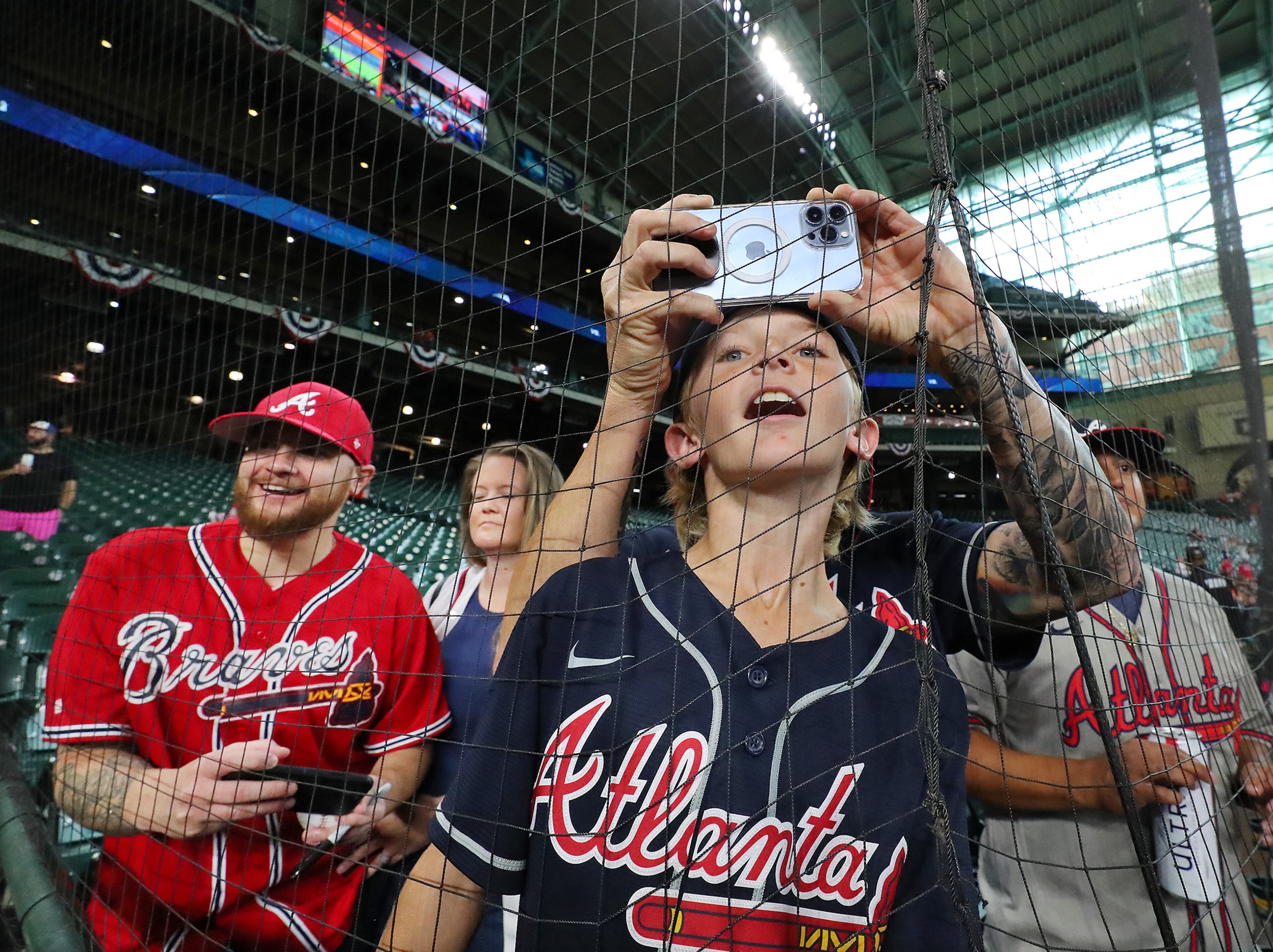Braves fan Ed Heyward snaps a photo of Freddie Freeman while his son Jimmy, 10, pushes up against the third base net to watch his team prepare to play the Astros at Minute Maid Park in game 1 of the World Series on Tuesday, Oct. 26, 2021, in Houston. “Curtis Compton / Curtis.Compton@ajc.com”