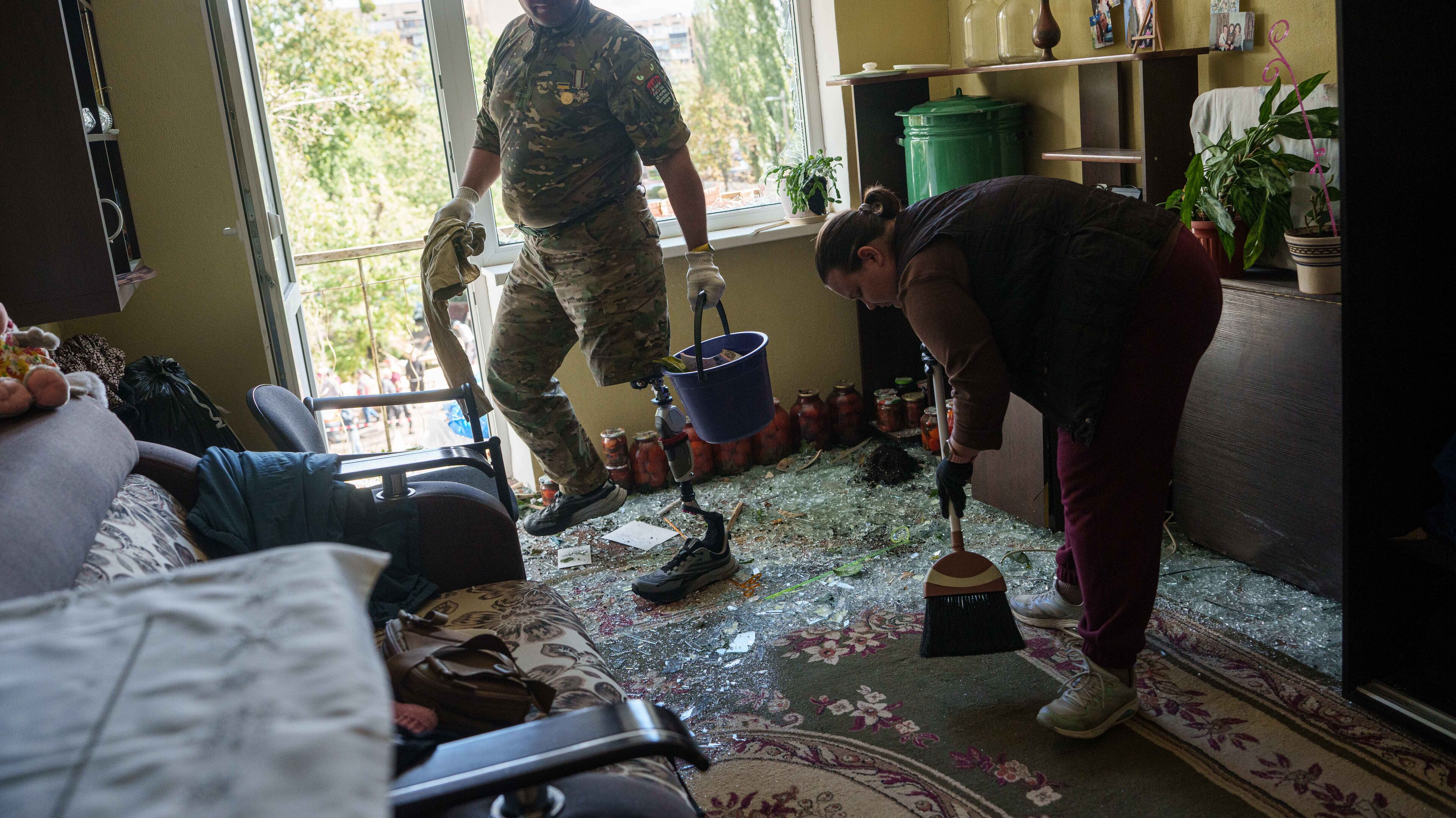 Oleksii, a Ukrainian war veteran, clears broken glass inside an apartment building damaged by a Russian drone strike in Kyiv, Ukraine, Tuesday, Sept. 22, 2026. (AP Photo/Evgeniy Maloletka)