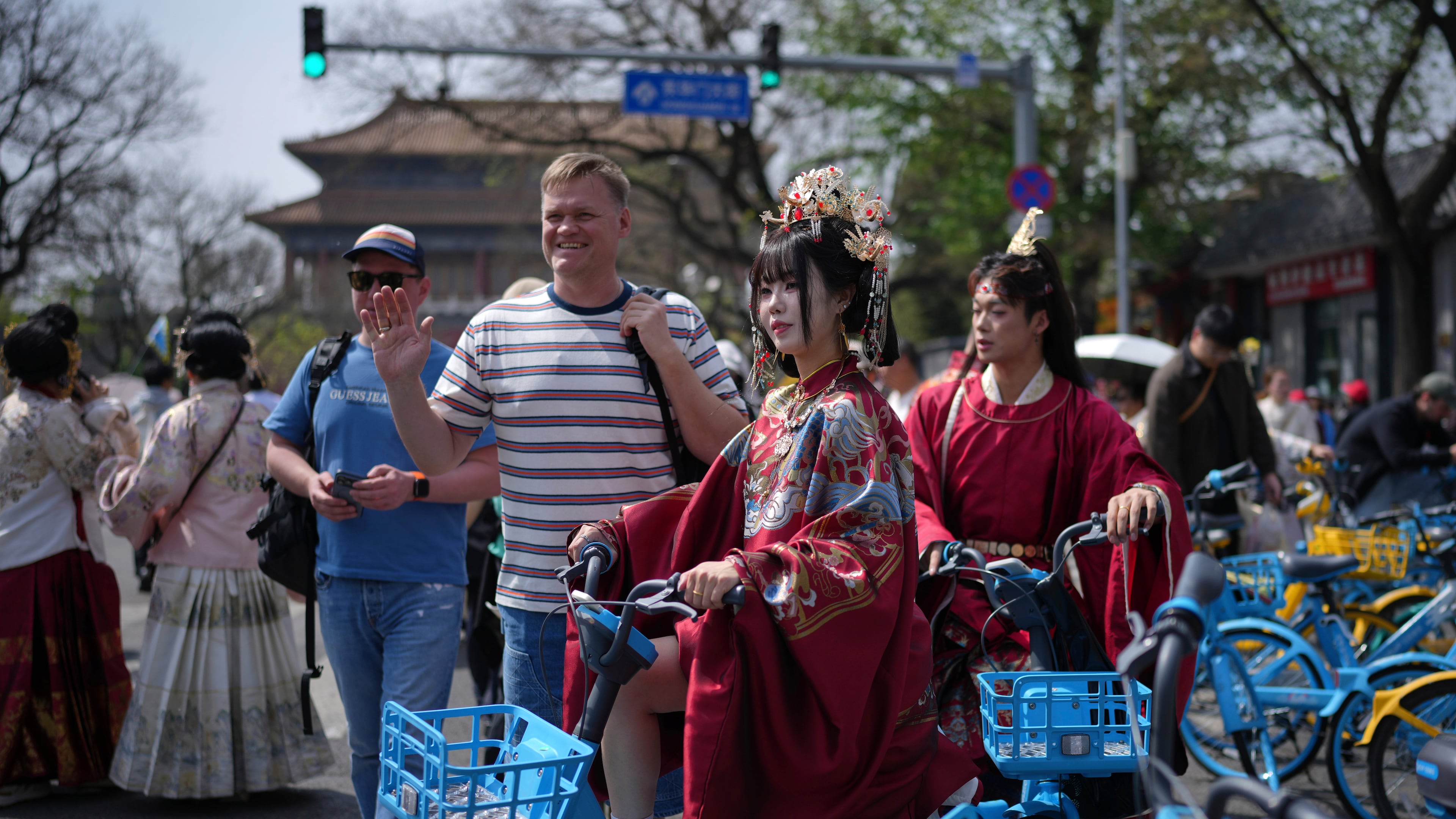 A foreign tourist poses next to a Chinese couple dressed in imperial costumes near the Forbidden City, in Beijing, on Sunday, April 12, 2026. (AP Photo/Andy Wong)