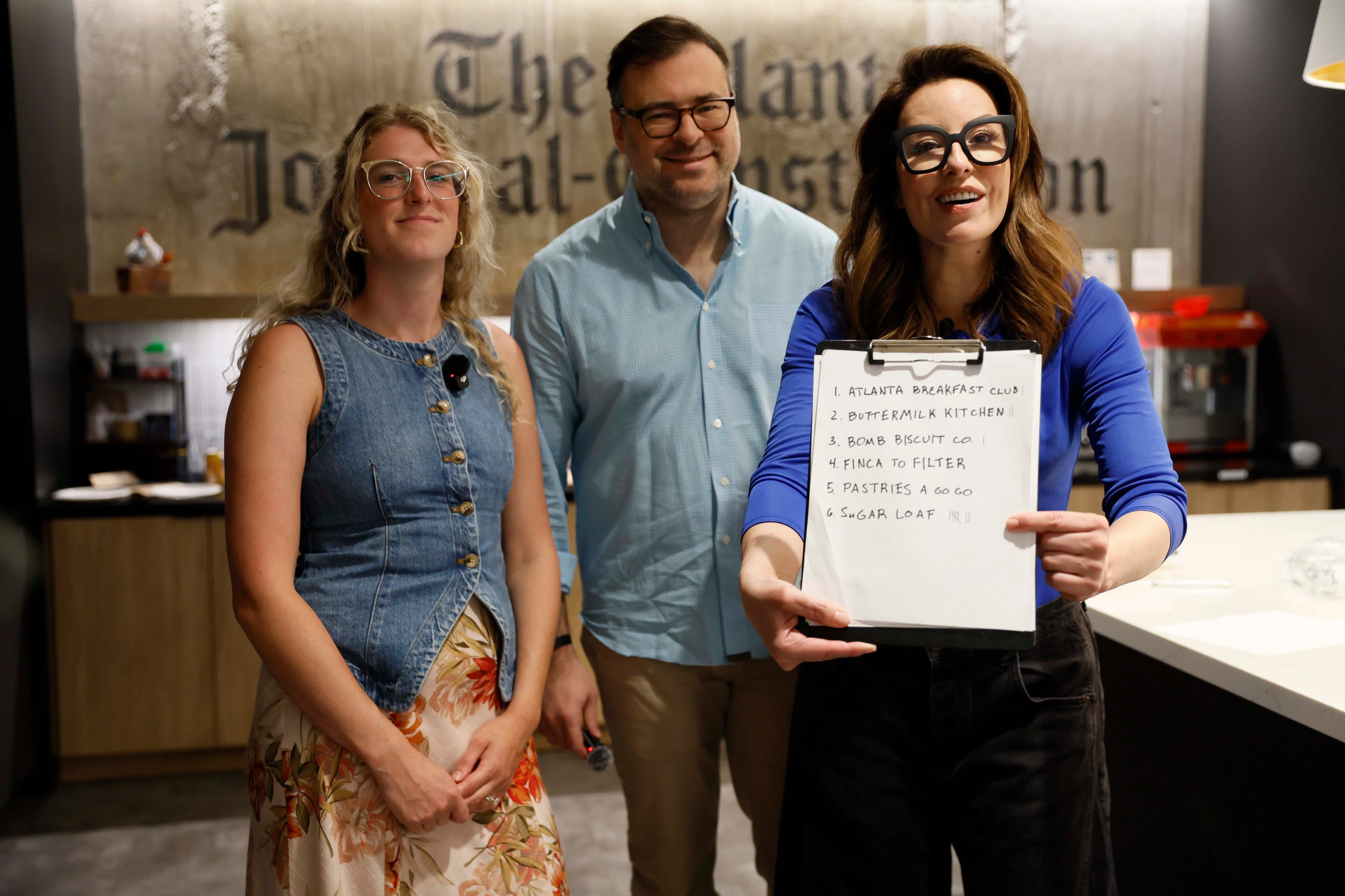 AJC Senior Food & Dining Editor Monti Carlo points to the winner, Sugar Loaf, during the biscuit taste test while standing with AJC restaurant critic Henri Hollis and Lifestyle reporter Olivia Wakim on Tuesday, April 28, 2026. (Miguel Martinez/AJC)