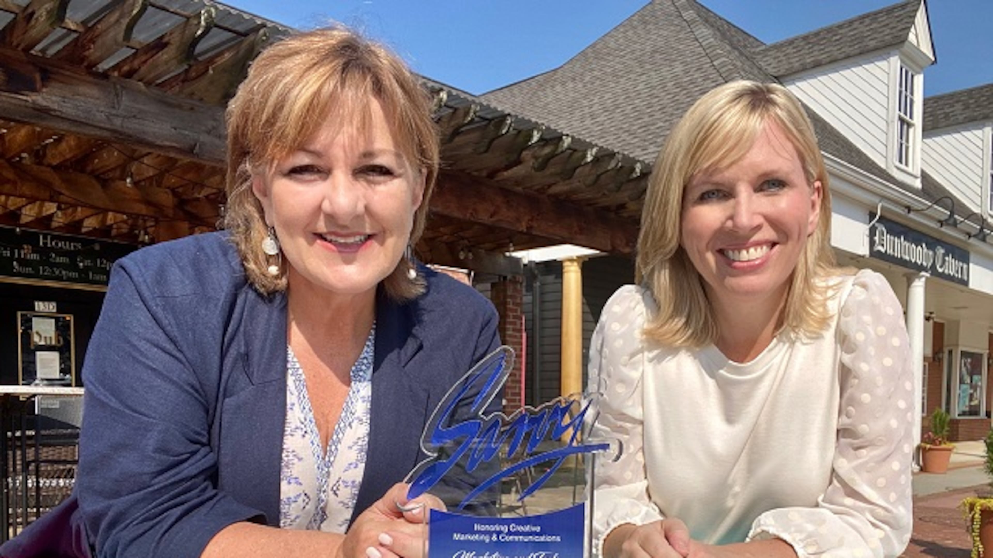For helping Dunwoody restaurants during the COVID-19 pandemic, (L-R) Dunwoody Communications Manager Kathy Florence and Dunwoody Communications Director Jennifer Boettcher pose with the Savvy Award at a painted picnic table in the Dunwoody Village. (Courtesy of Dunwoody)