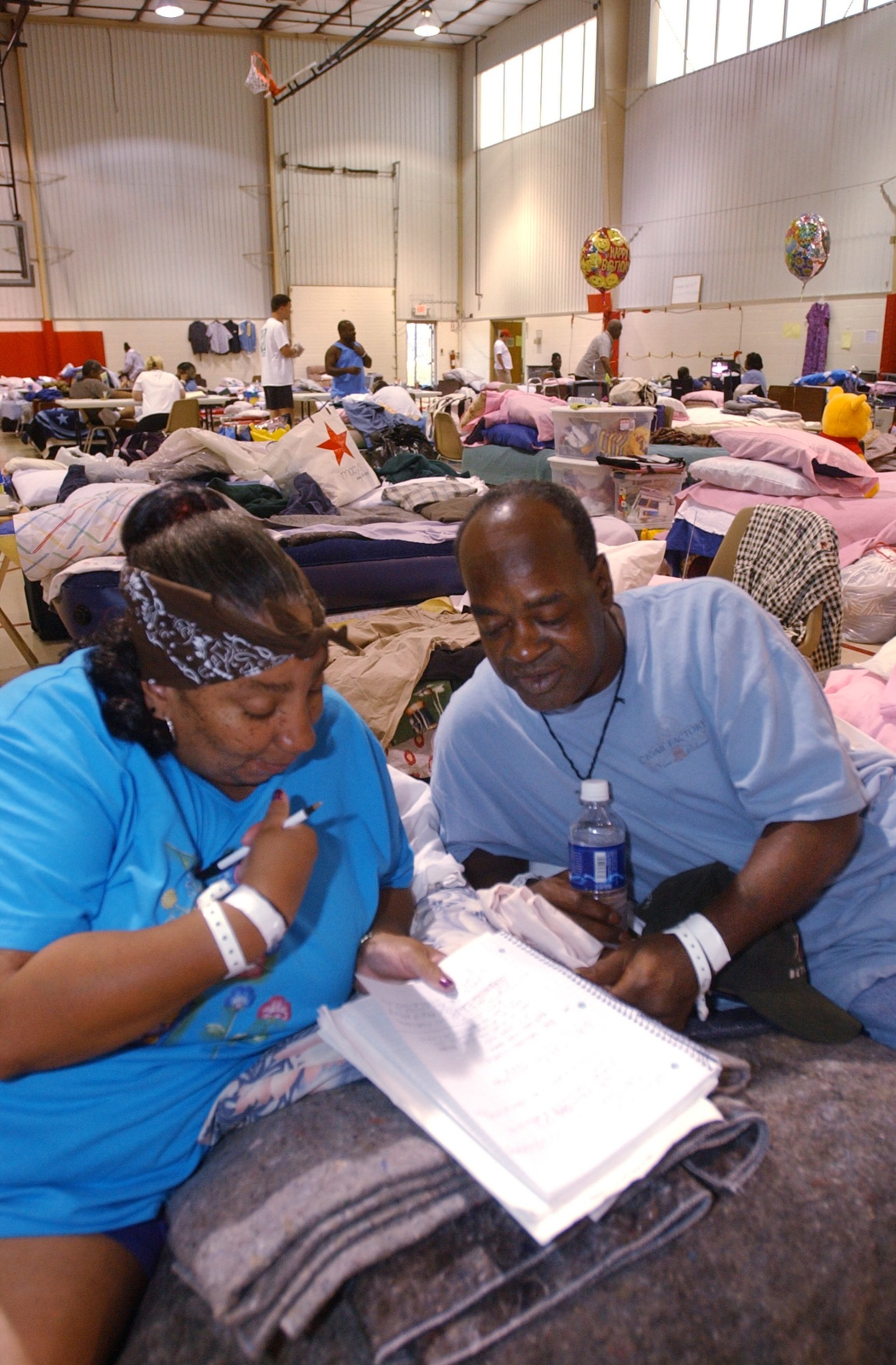 050910 COBB COUNTY, GA: Katrina evacuees Lora Glover (cq) left, and her husband Horace Glover (cq) right, of New Orlenas, LA go over a notebook filled with information as they formulate a plan of action at the Red Cross Shelter at the Boots Ward Recreation Center in west Cobb County Saturday 9/10/05. NOTE: Mrs. Glover is already pictured in "Cobbshelter 02." (Kimberly Smith/staff)