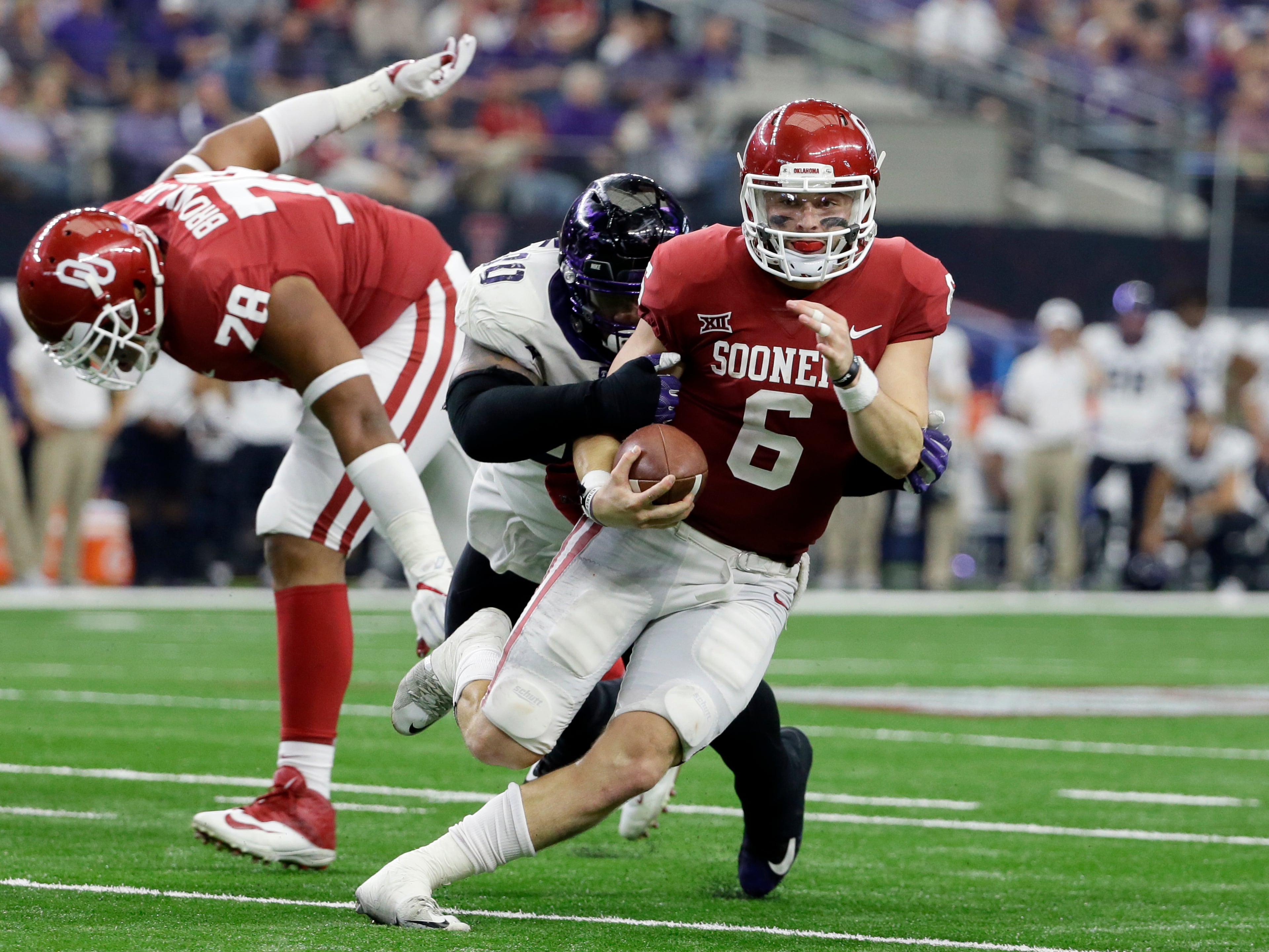 Oklahoma quarterback Baker Mayfield, front, is chased out of the pocket by TCU defensive tackle Ross Blacklock, rear, in the second half of the Big 12 Conference championship NCAA college football game, Saturday, Dec. 2, 2017, in Arlington, Texas. (AP Photo/Tony Gutierrez)