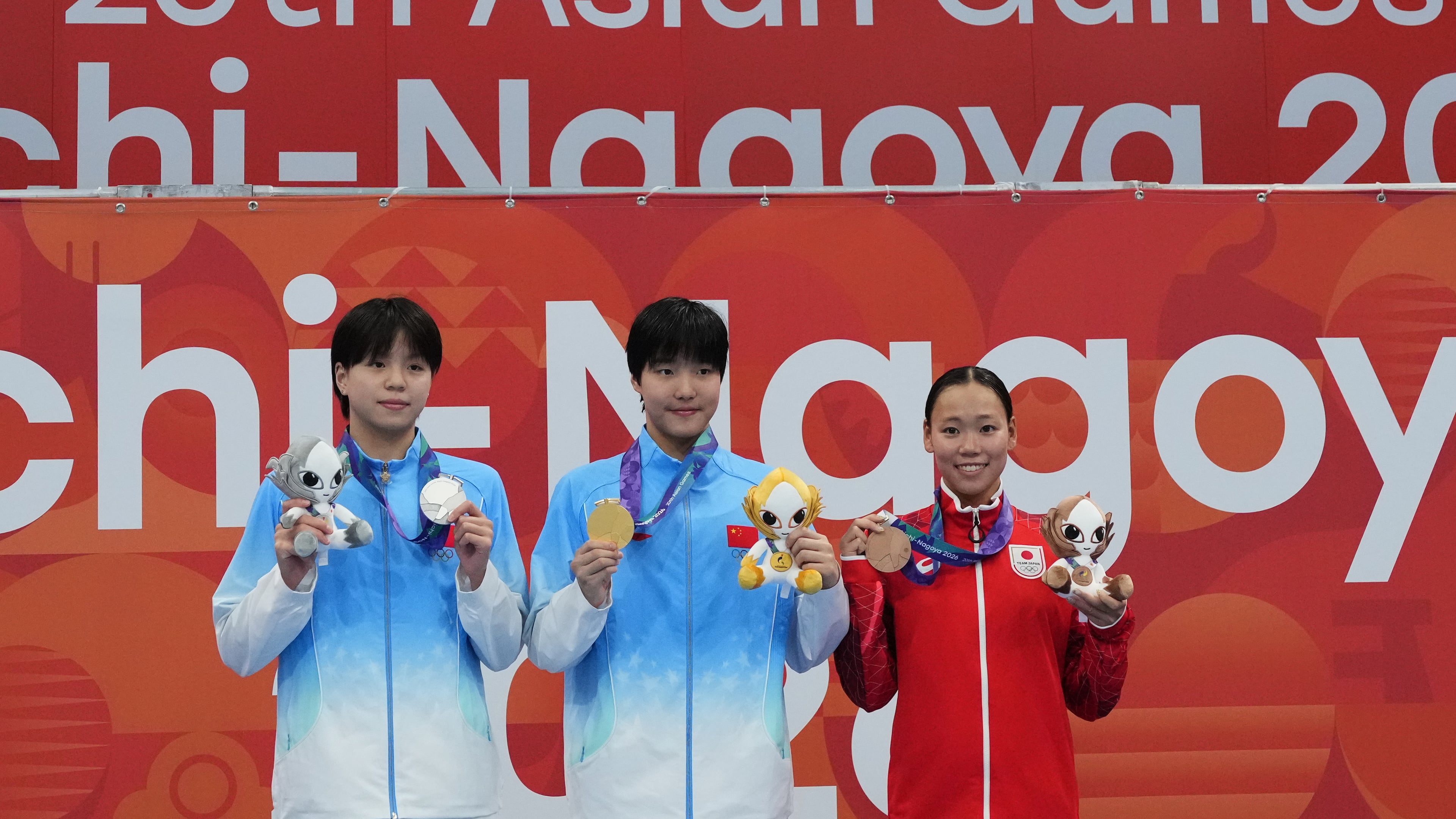 Gold medalist Yu Zidi of China, center, flanked by silver medalist Chang Mohan of China, left, and bronze medalist Misa Okuzono of Japan pose on the podium after the women's 200-meter butterfly final in swimming at the Asian Games in Tokyo, Japan, Sunday, Sept. 20, 2026. (AP Photo/Hiro Komae)