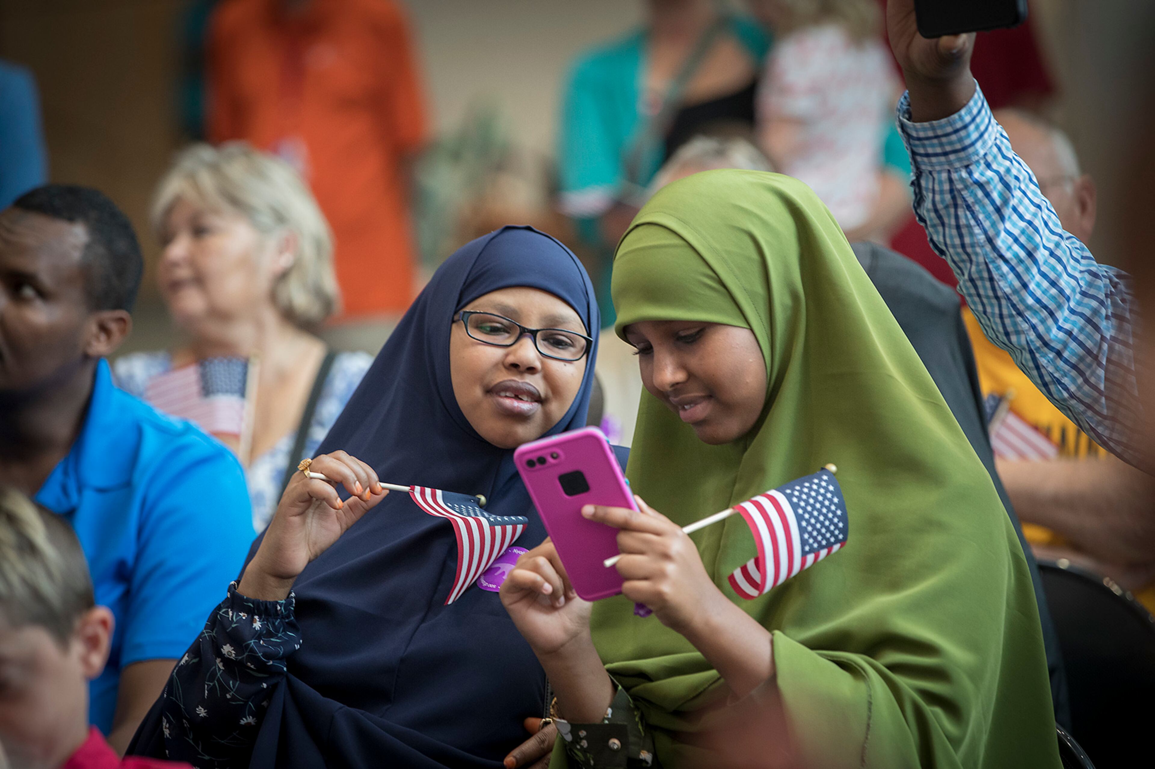 Samiira Osman, left, and Riyaq Aden, looked over pictures they took of Osman's son Yahye Mohamud during a U.S. Citizenship and Immigration Services citizenship ceremony at the Minnesota Children's Museum, Friday, July 21, 2017 in St. Paul, Minn. (Elizabeth Flores/Star Tribune via AP)