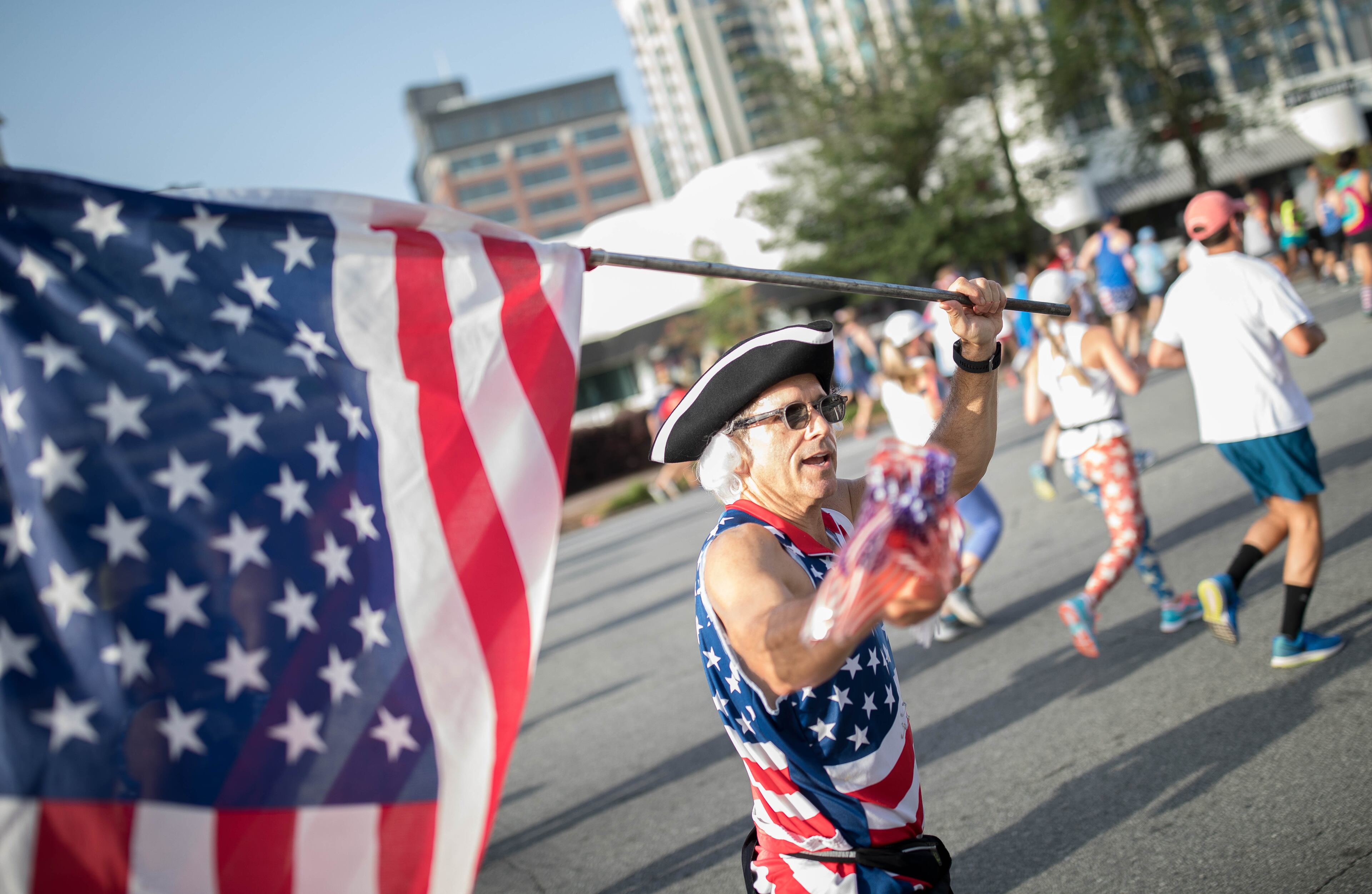 A man runs with an American flag as he makes his way down Peachtree Street during the 48th AJC Peachtree Road Race, Tuesday, July 4, 2017, in Atlanta. BRANDEN CAMP/SPECIAL