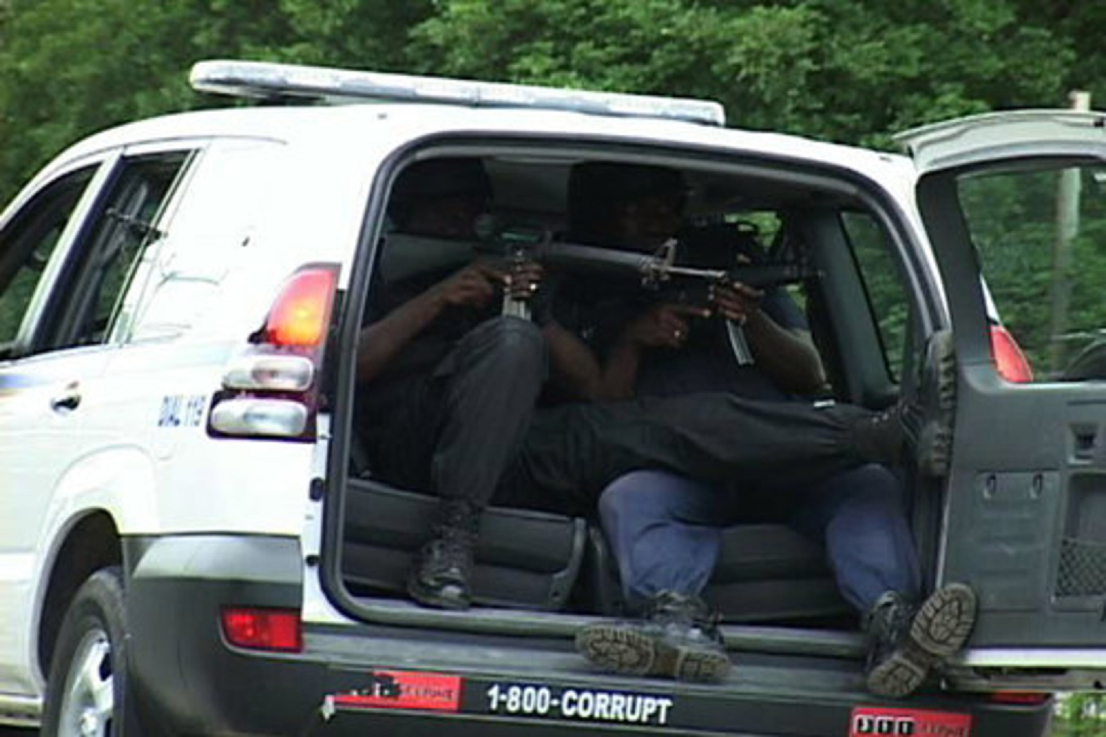 Police officers aim weapons from inside a police vehicle in Kingston.