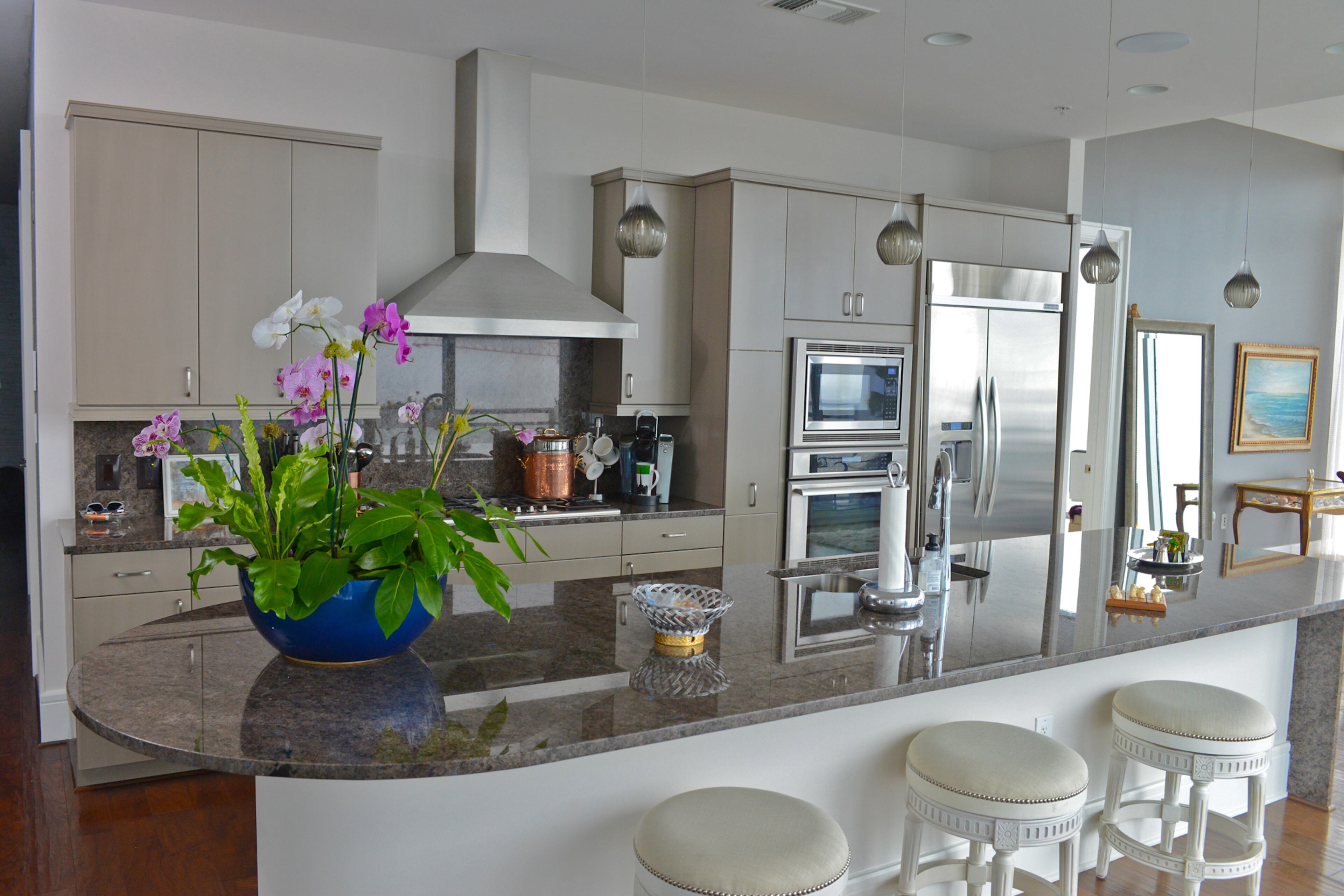 A vibrant orchid configuration on the kitchen counter, by PFI (also known as Plants Forever Inc.) adds color and brings to life the modern gray kitchen with stainless steel appliances in Jim Wilson's Midtown condo. Painting and lighting renovations throughout the home were done by Building Revolutions.