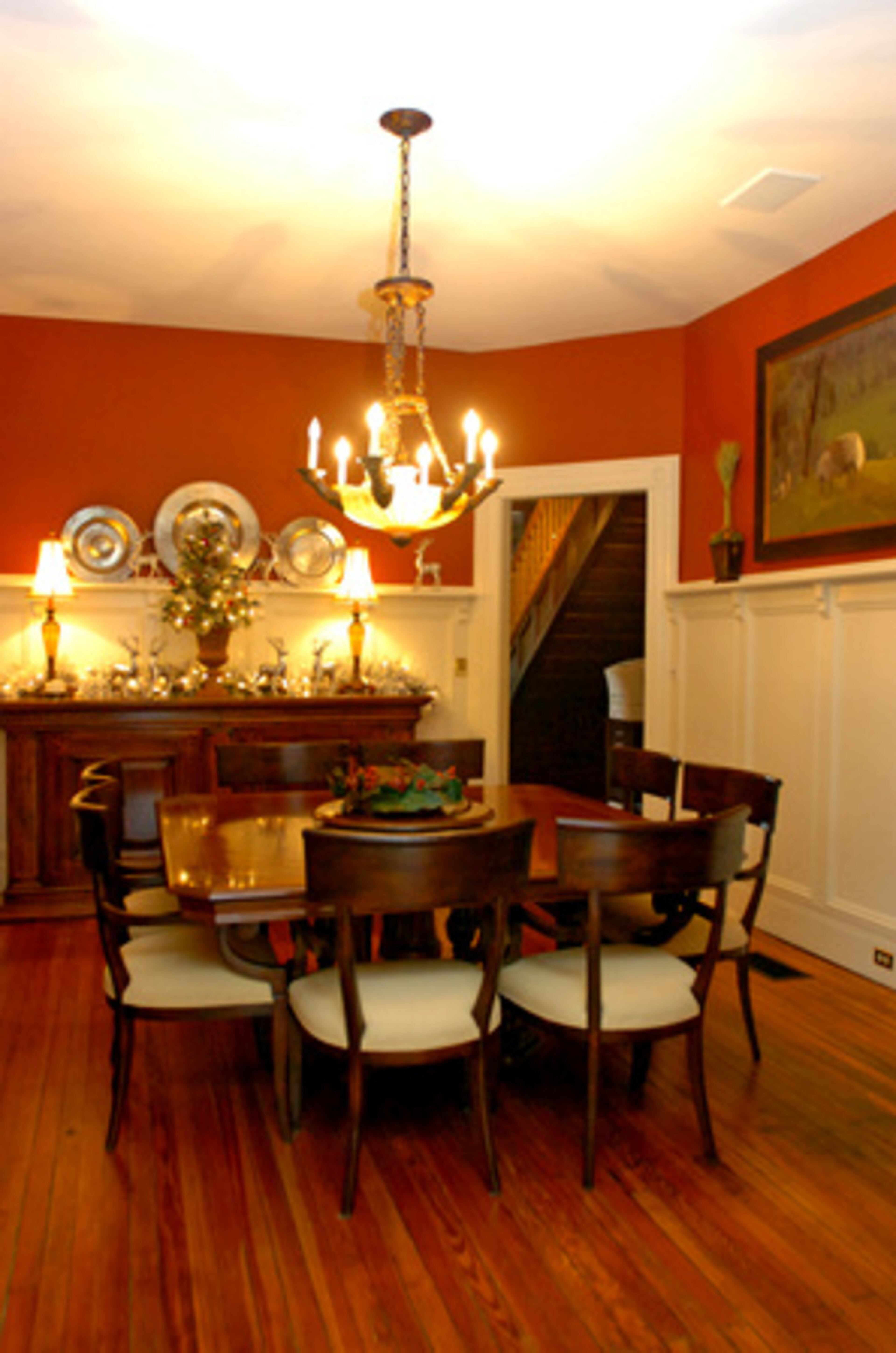 The informal dining room features wainscoting and deep red walls. The table is made from 300-year-old wood.